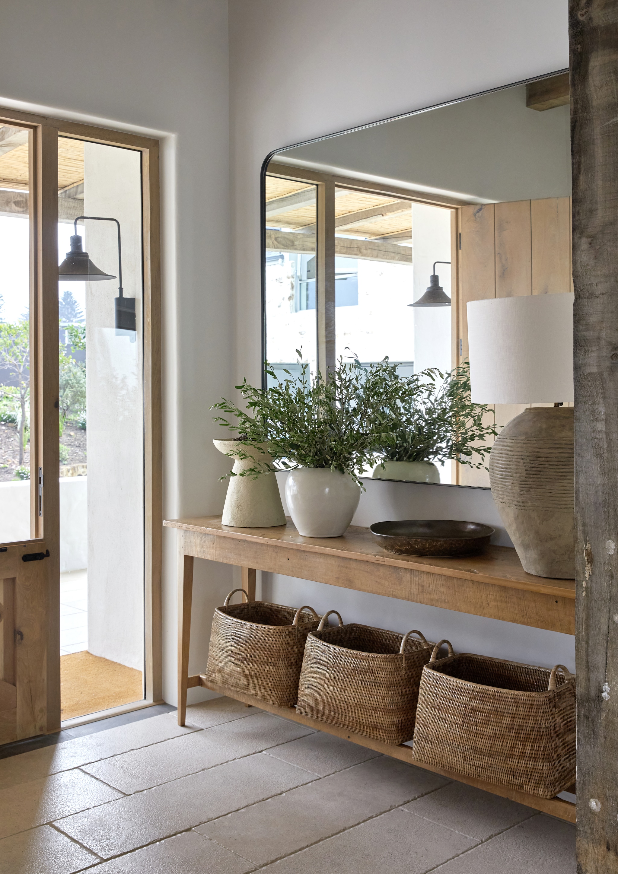 Sidetable antiek. Soortgelijke maatwerkspiegels met afgeronde hoeken AtelierD. Vergelijkbare lampen Loberon en Zara Home. Op de vloer liggen kalkstenen tegels. vtwonen landelijk 8-2026 | Styling Luanne Toms | Fotografie Greg Cox