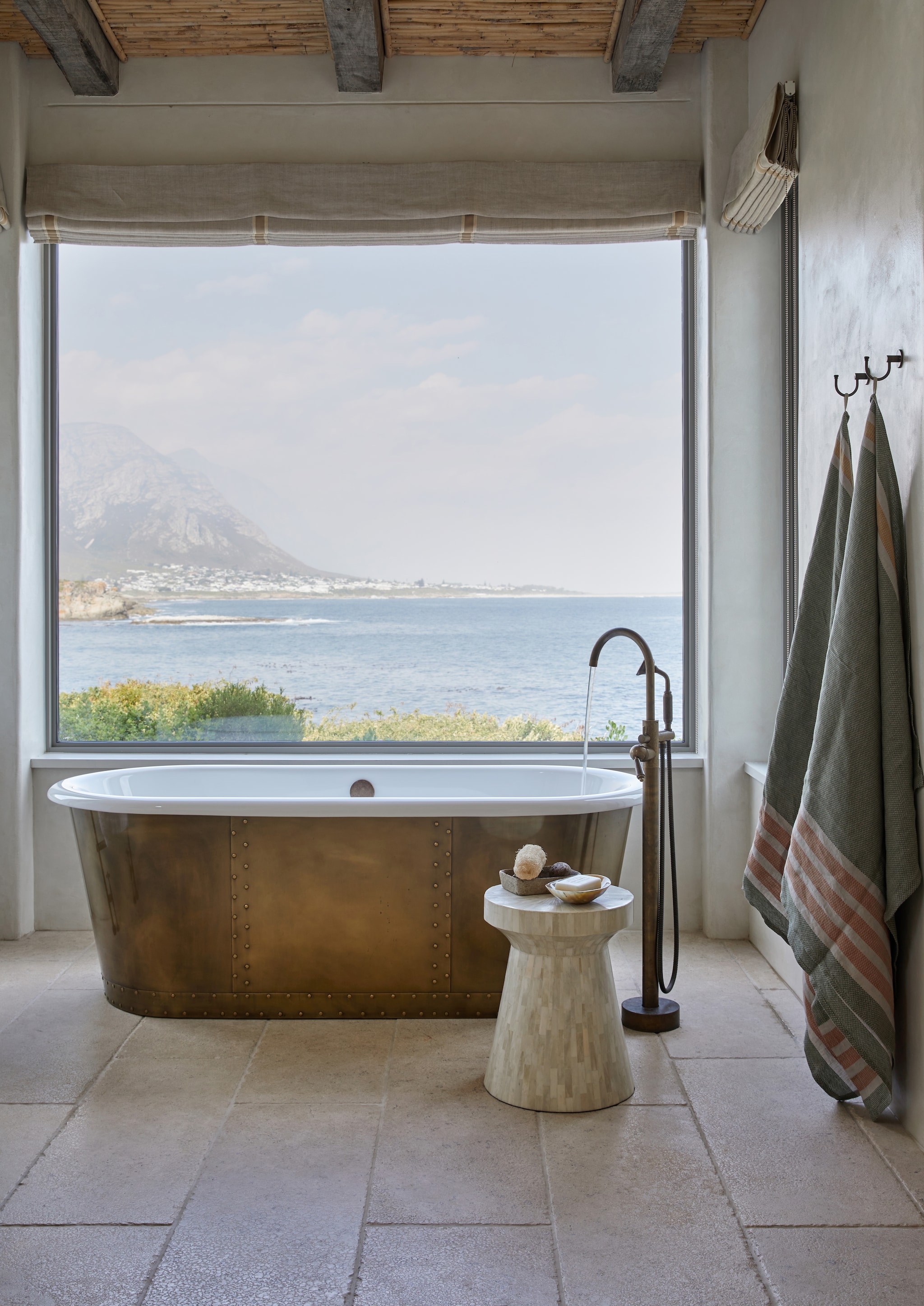 Vergelijkbaar koperen bad Hudson Reed of The Classic Home. Vloertegels kalksteen. Bijzettafel Cécile & Boyd. Vergelijkbare badkraan Cobber van Hotbath. vtwonen landelijk 8-2026 | Styling Luanne Toms | Fotografie Greg Cox