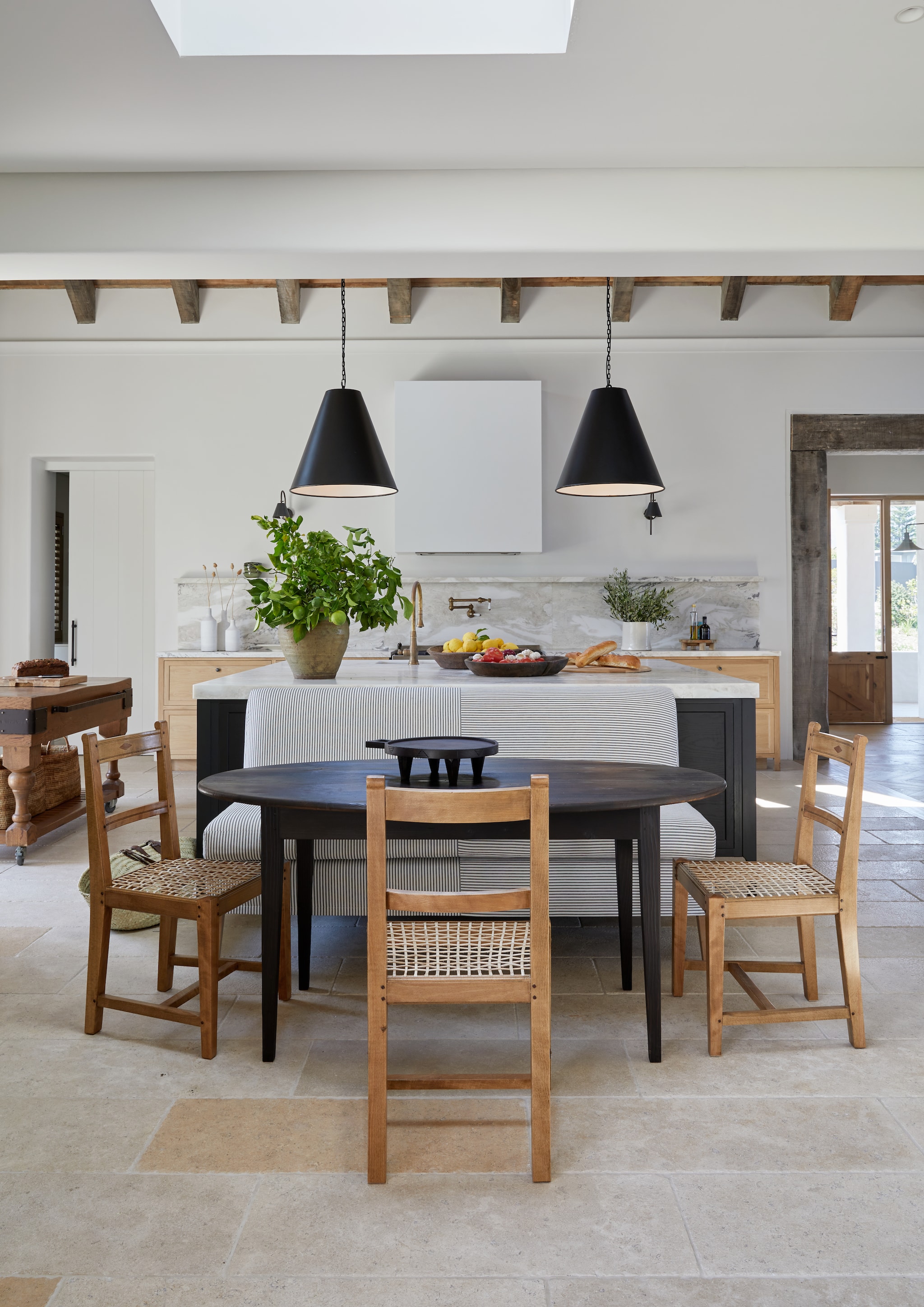 Ovale tafel op maat gemaakt. Eikenhouten stoelen Binedell van @arkworkshop. Maatwerk eettafelbanken te vinden bij Table du Sud en Bankstyle. Kalkstenen vloertegels. vtwonen landelijk 8-2026 | Styling Luanne Toms | Fotografie Greg Cox