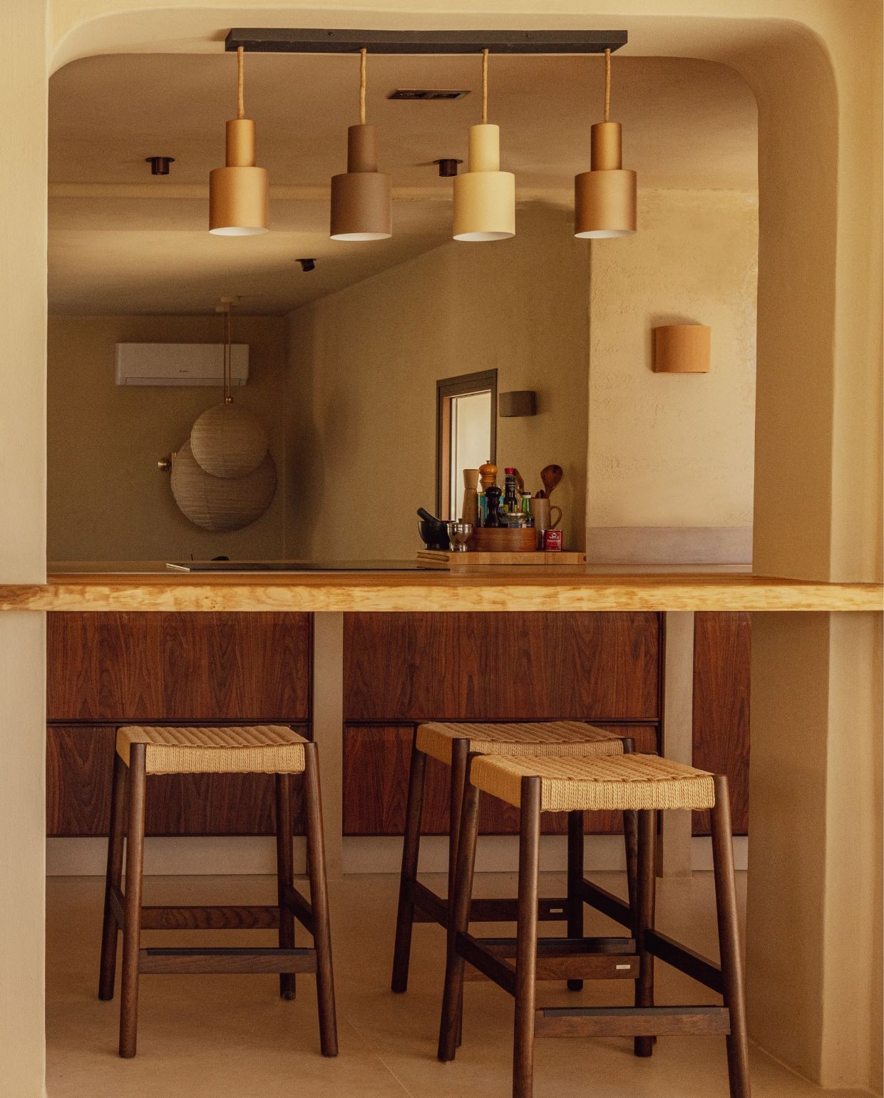 Muur- en plafondkleur lokale kalkverf & leemstuc Arena. Eikenhouten blad lokaal ingekocht en ter plekke op maat gezaagd. Hanglampen lokale lampenwinkel. Wandlamp lokaal keramiek. Barkrukken Kave Home. Ronde lampionnen The James Haarlem.