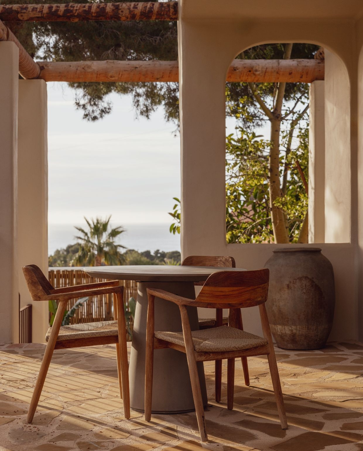 De veranda aan de achterkant van het huis is een heerlijke plek om in de zomermaanden in de schaduw te zitten. Buitentafel Kave Home. Buitenstoelen Ibiza Outdoor. Pot van de antiekmarkt in Jalón. vtwonen Zomerspecial 2026 | fotografie Dana van Leeuwen