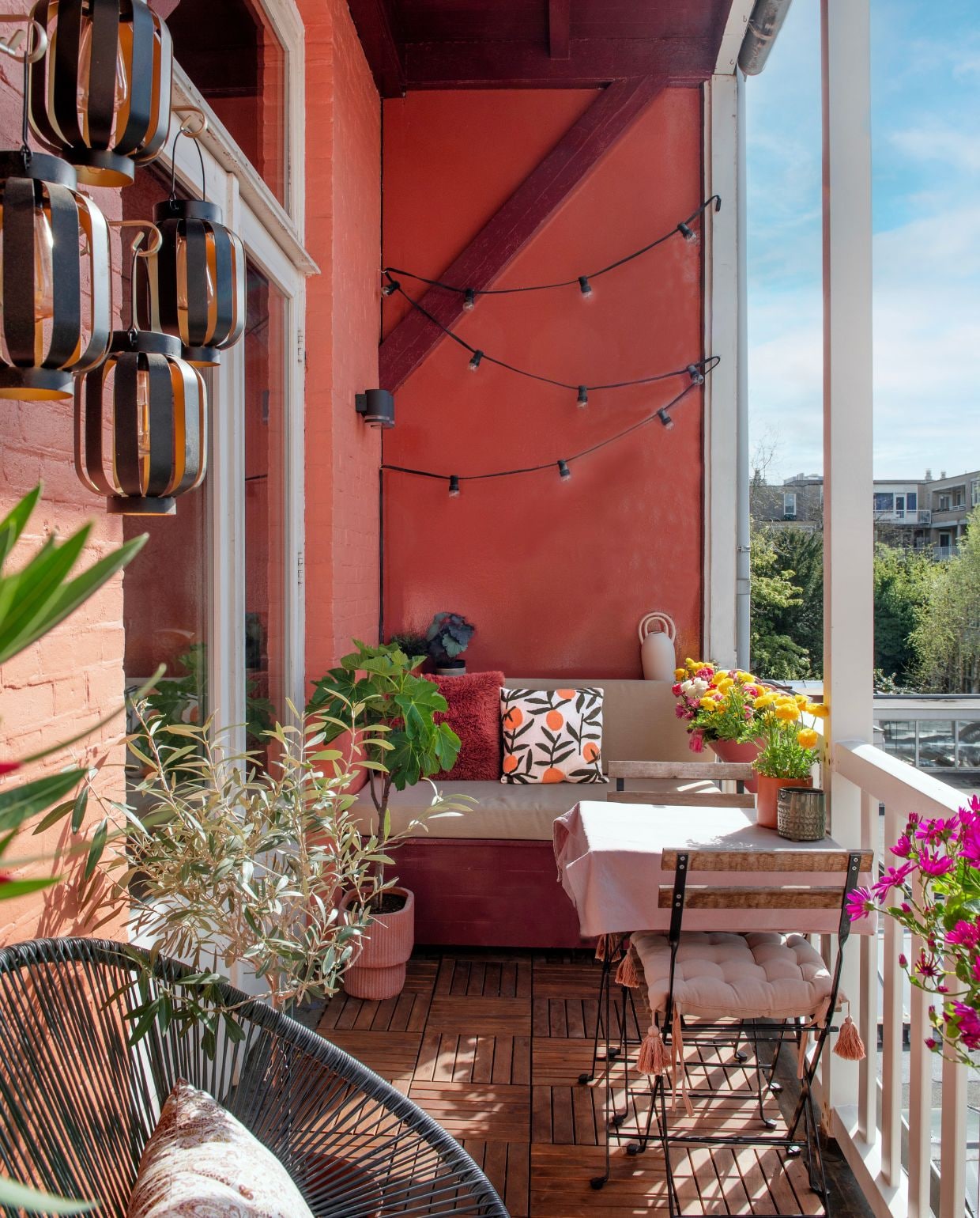 Lantaarns en kussens Karwei, lichtslinger Sissy-Boy, zitkussens Nofruit, bistroset Ikea, tafelkleed Jotex. Muurverf Red Earth, verf zijwand Eating Room Red en verf houten bank en schuine balk Preference Red van Farrow & Ball. Overig onbekend.