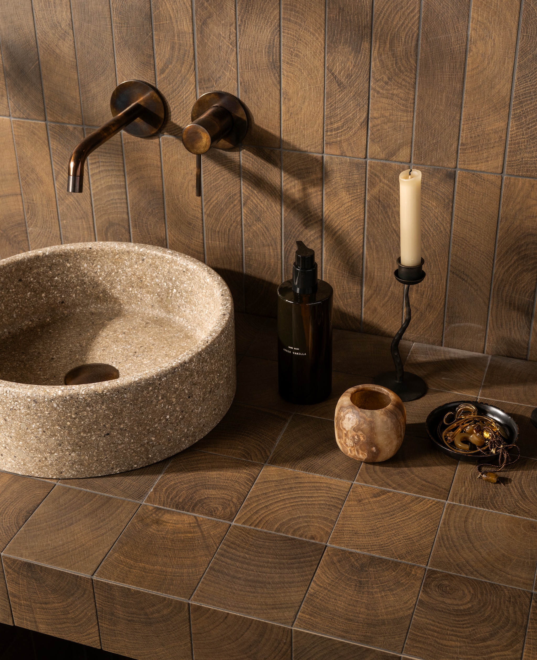 vtwonen vloer- en wandtegel Woodcirkle, keramiek, wenge, 10x10 cm  (lxb) en 30x5,3 cm (lxb), per m2 vanaf € 76,50. M.m.v. detremmerie.nl (waskom).douglasjones.nl (wastafelkraan), zarahome.com (spiegel, wandlamp, kandelaars, zeeppomp). Overig privébezit. vtwonen Landelijk 08-2026 | styling Kim van Rossenberg | fotografie Stan Koolen