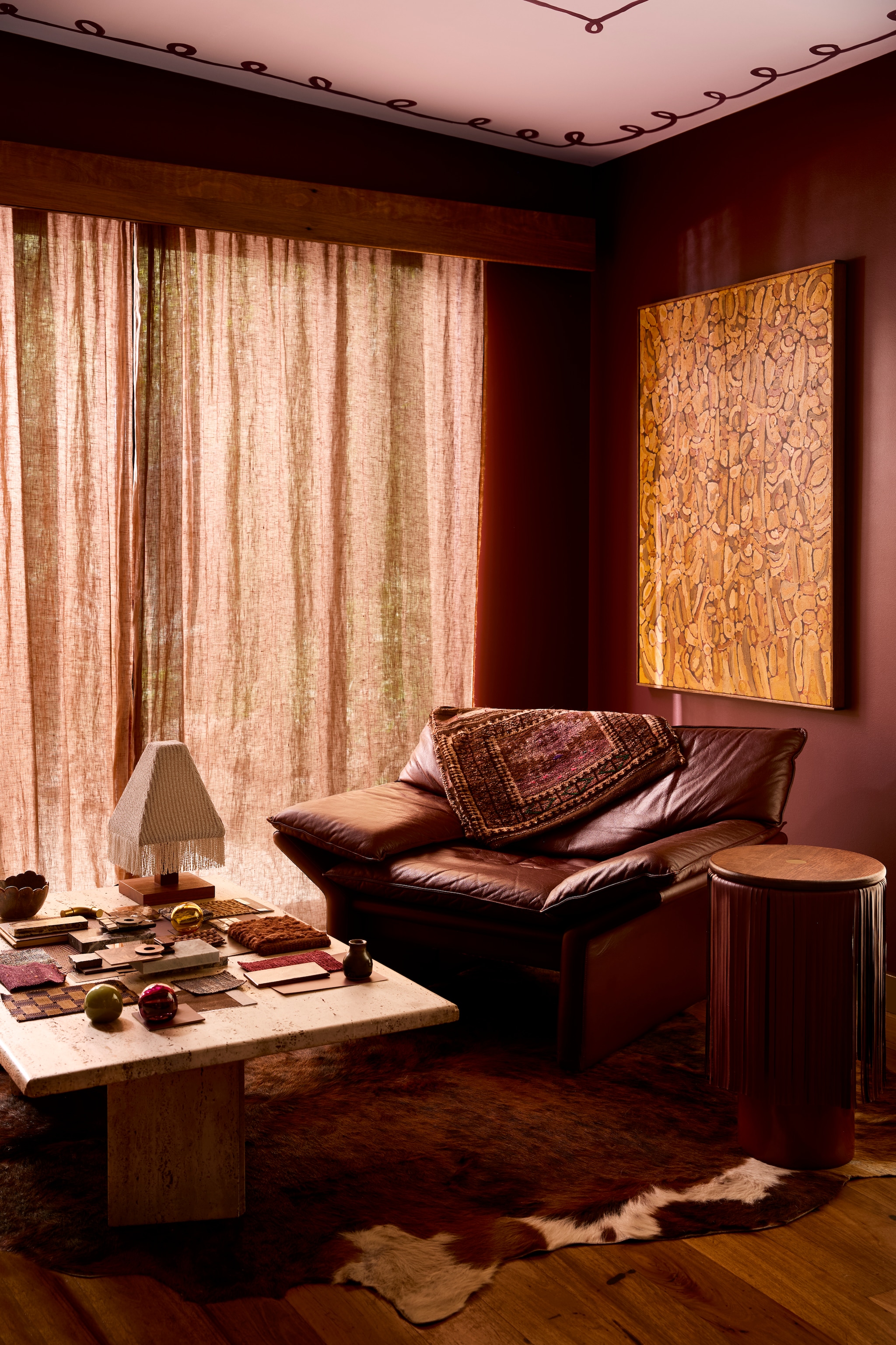 Ruby’s Studio. Muurkleur Plumb Sauce, plafondkleur Hint of Lavender, beide Dulux. Kunstwerk Joshua de Gruchy. Ronde bijzettafel Orville van Locki Humphrey. Vintage fauteuil via Robinson’s Furniture met daarop oude zadelzakken van Najaf Rugs. Tafellamp Cubozoa van Curtis Bloxsidge x 2am Close. Vintage travertijn bijzettafel via Curated Spaces. vtwonen Trendspecial 2026 | fotografie Martina Gemmola