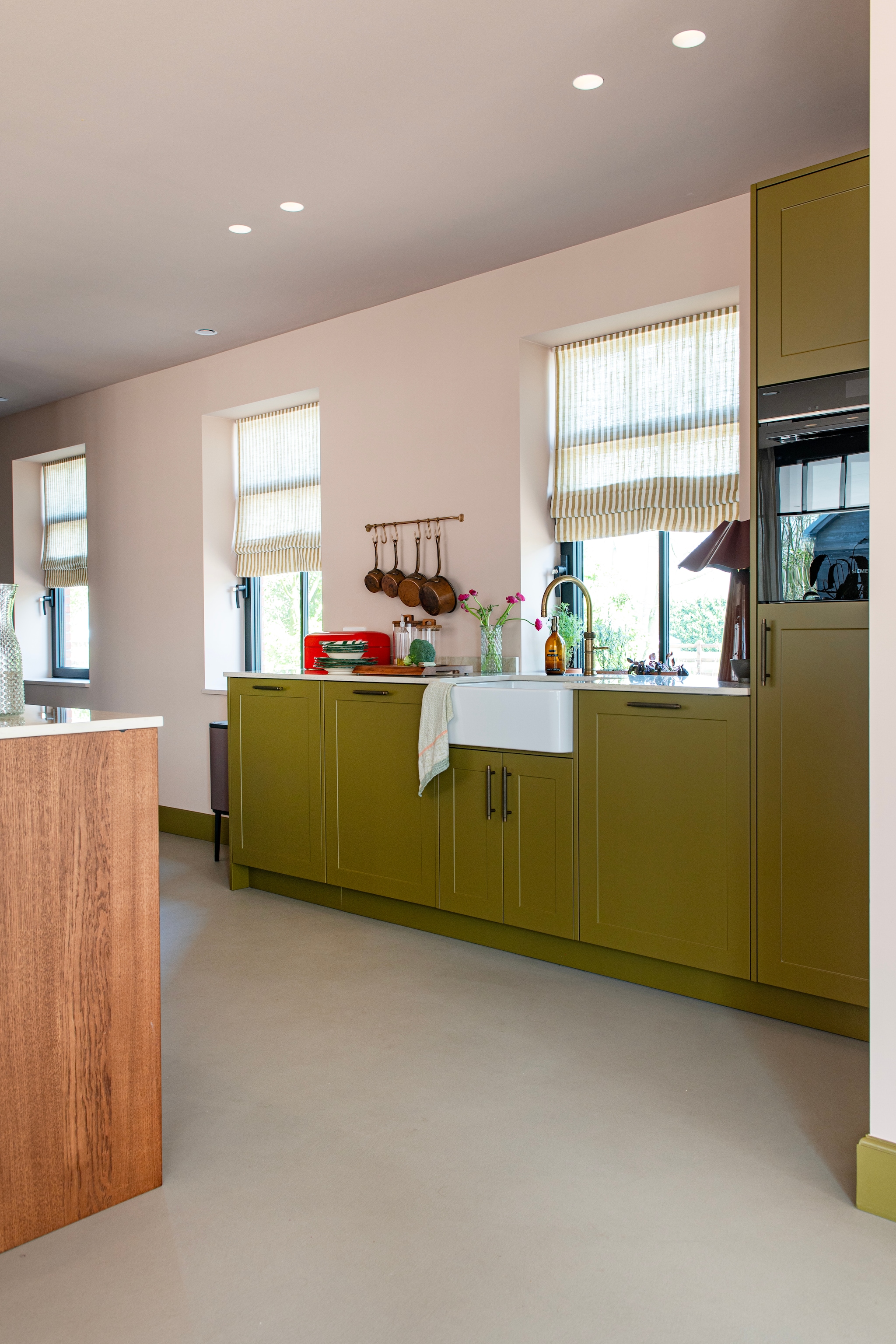 Keukeneiland met eiken fronten en natuurstenen blad. Keuken maatwerk Eik-punt. Vouwgordijnen Gotain. Tafellamp Loods 5. Gietvloer van lavasteen. Kastgreepjes Dauby. vtwonen Special 03-2026 | fotografie Caroline Coehorst | productie De Binnenkijkers by Caroline
