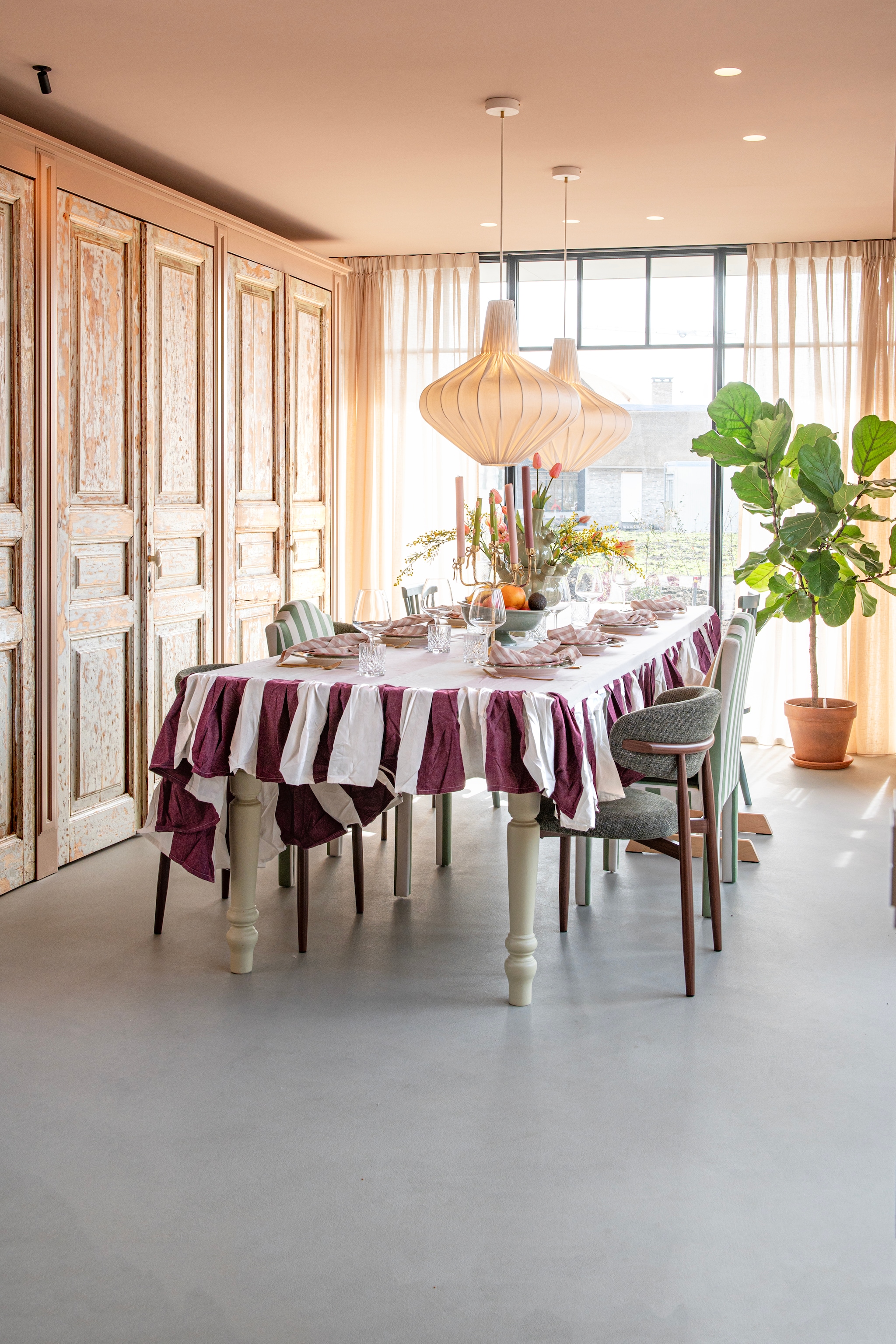 Tafelkleed Pien’s Tables. Maatwerk tafel Van Dijk & Ko. Oude kastdeuren Oude Deur. Gordijnen Karwei. Bruine eetkamerstoelen Giga Meubel. Gestoffeerde stoelen Maison Flâneur. Lamp Sézane. vtwonen Special 03-2026 | fotografie Caroline Coehorst | productie De Binnenkijkers by Caroline