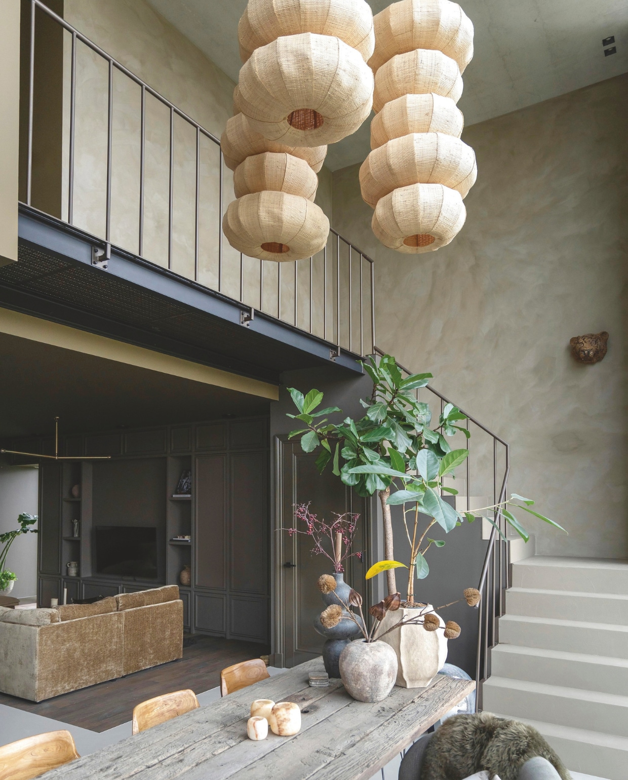 Jet combineerde meerdere lampen, vergelijkbaar met Zosia van Light & Living, tot deze hanglampen. Bank Spektakel Wonen. Soortgelijk: vaas rechts model L van Ernst, waxinelichthouders Solulu. Op de trap beton ciré 940 Honey van Betonstunter. Wand boven trap kalkverf Mud Soldier van Lab colour the world. Wand onder trap Sand Storm van Pure & Original. Wandkast woonkamer Soho van Lab colour the world. Plafond zithoek F4.16.22 van Sikkens. vtwonen 05-2026 | styling Jet Hendriks | fotografie Lotte van Uittert