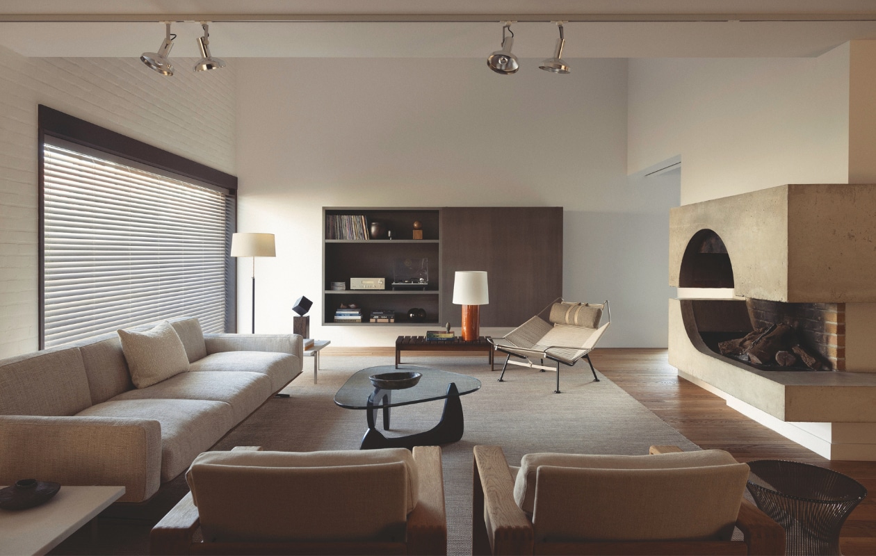 Zwevende kast en tafellamp Lisboa, ontworpen door Stef Claes. Bank Flexform via RR Interieur. Vintage tafels naast bank Poul Kjærholm. Kubuskunstwerk Pol Bury. Salontafel Isamu Noguchi, aardewerk erbovenop Pierre Culot. Vintage stoelen en houten tafel Martin Visser via Céline Hellin. Stalamp Santa & Cole. Fauteuil Flag Halyard van Hans J. Wegner voor Pp Møbler.