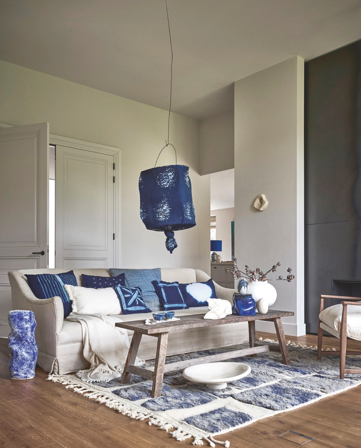 Heartwear lamp, fairtrade, indigo, prijs op aanvraag, vintage geruit kussen, fairtrade, indigo € 350,-, Heartwear handbedrukte kussens, fairtrade, indigo, per stuk € 75,- (mvninteriors.com). Beni Mguild vloerkleed 42300, wol € 790,- (rozenkelim.nl). Aura Peeperkorn koffietafel, hout, 120x50x50 (lxbxh) € 475,-, plaid € 99,- (aurapeeperkorn.com). Atelier de Rijk bijzettafel, keramiek, blauw, decoratief ei en voet op tafel, keramiek, kunst aan de wand, prijs op aanvraag (atelierderijk.com). Zara Home fauteuil, essenhout, linnen € 359,- (zarahome.com). Madam Garage tafellamp in doorkijk, maatwerk vanaf € 169,- (madamgarage.nl). Household Hardware schaal, tadelakt, naturel, 46x11 cm (Øxh) € 159,-, Urban Nature Culture vaas Camilla, aardewerk, wit, 31x27 cm (Øxh) € 89,99 (shop.vtwonen.nl). Japanse theekopjes, keramiek, prijs op aanvraag (japansetheepot.nl). Overig privébezit. vtwonen Landelijk 05-2026 | styling Kelly van Gendt en Liza Wassenaar | fotografie Alexander van Berge