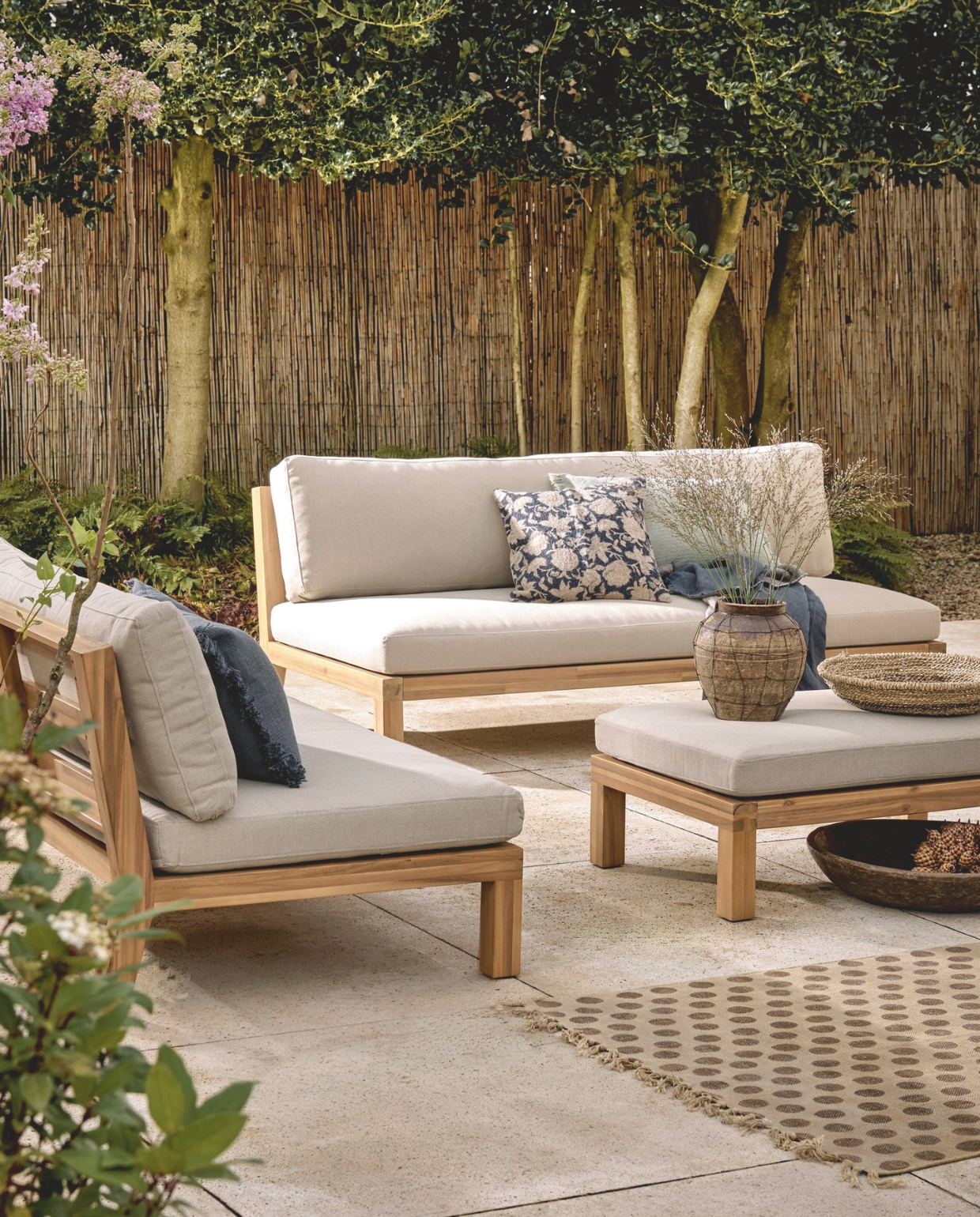 vtwonen hocker/bijzettafel Relax, fsc-gecertificeerd acaciahout en polyester kussen in naturel/zand, 90x60x40 cm (bxdxh) € 349,-. tuinbank Relax, fsc-gecertificeerd acaciahout en polyester kussens in naturel/zand, 180x90x70 cm (bxdxh) € 749,-, vtwonen loungestoel Relax, fsc-gecertificeerd acaciahout en polyster kussens, naturel en zand, 120x70x90 (bxdxh) € 549,-. M.m.v. zarahome.com (kussens, vaas), hetkabinet.nl (mand, vloerkleed, grote houten schaal). Overig privébezit.