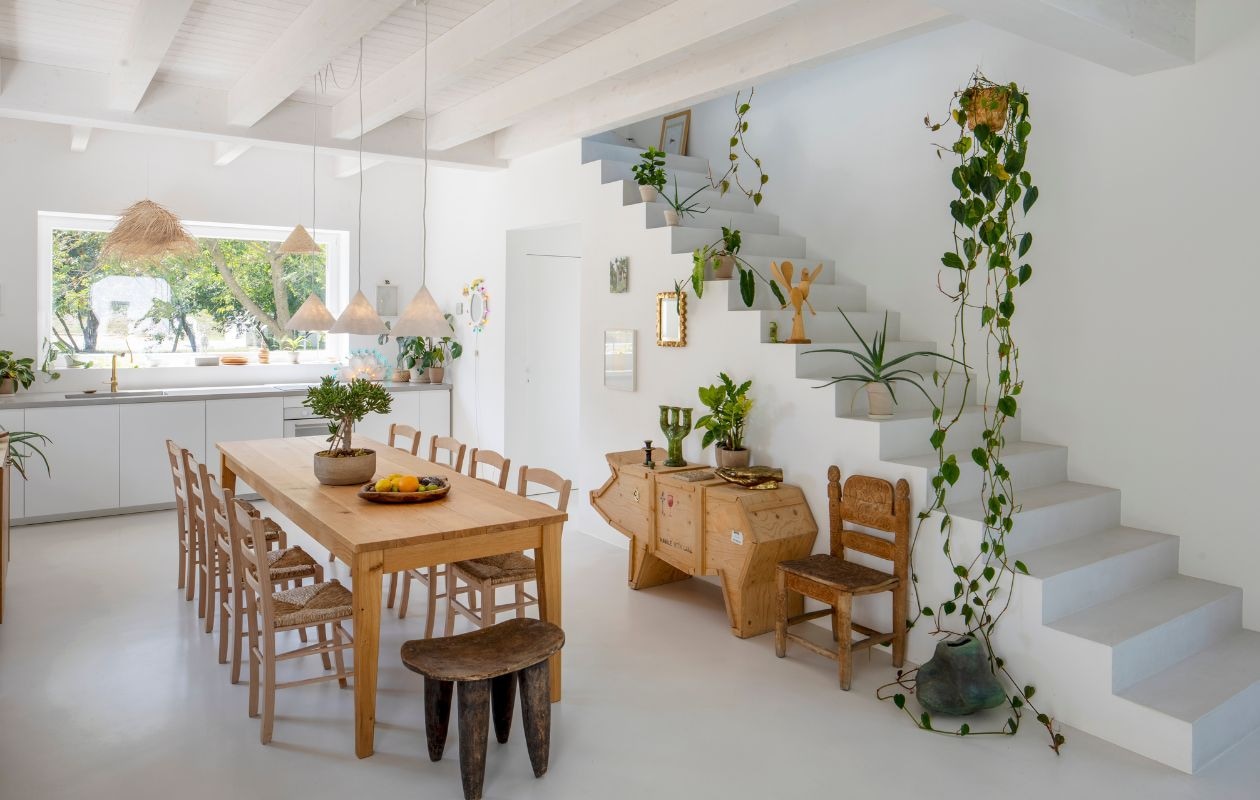 Boven de tafel papieren hanglampen ontworpen door Marcantonio. Dressoir Sending Pig van Seletti. Tamegroute kandelaars uit Marokko. Houten sculptuur in de vorm van een vogel gekocht in Brazilië. Eikenhouten tafel gemaakt door een bevriende timmerman. Typische Romagnoolse taverne-stoelen en een Afrikaanse kruk. Stoel naast de trap naar het slaapgedeelte gekocht op de antiekbeurs van Arezzo. Op de grond keramiek uit de jaren zeventig. Keukenkraan en wasbak Gusto van Ideal Standard. vtwonen Design 05-2026 | fotografie Helenio Barbetta