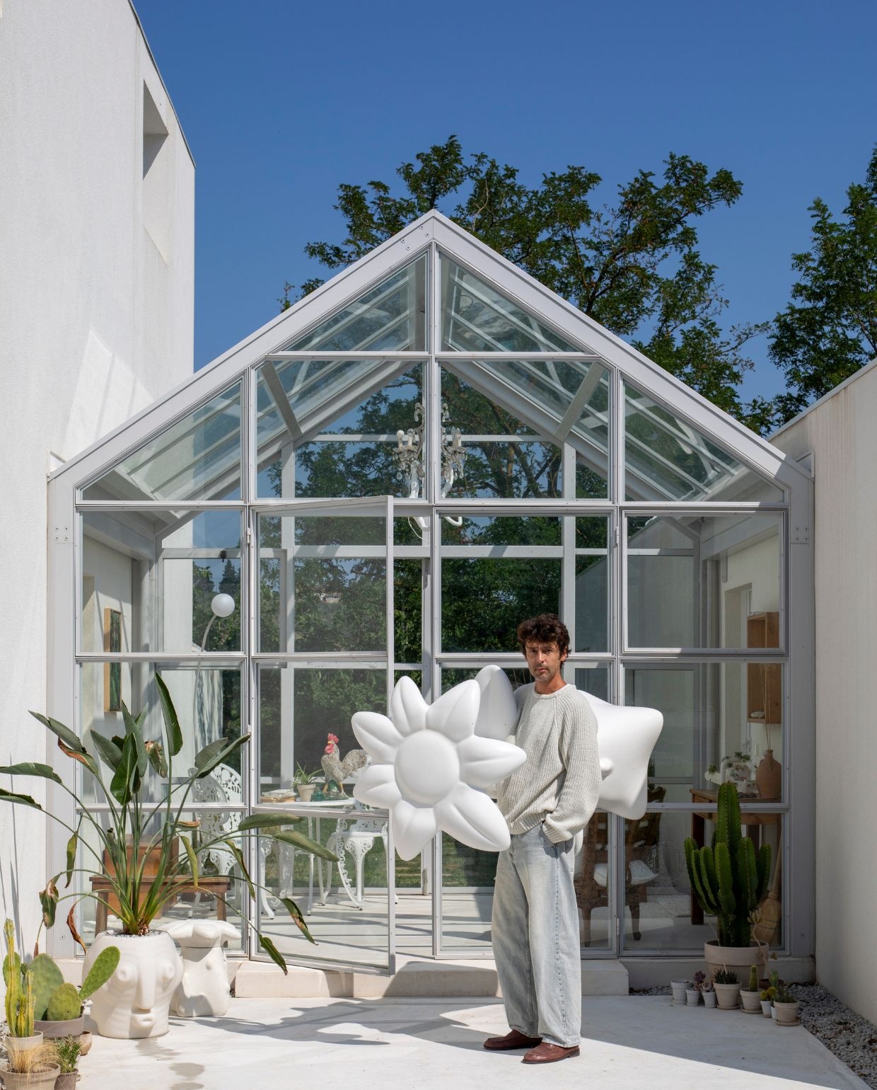 Marcantonio met een reusachtige glasvezelbloem onder de arm. Kruk met bloemblaadjes en pot Threebù van Slide. vtwonen Design 05-2026 | fotografie Helenio Barbetta
