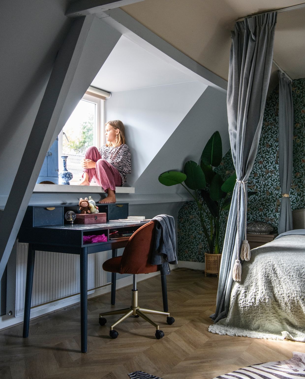 Bureau Maisons du Monde. Stoel Ikea. Vloer Tegels & Laminaat. Zebrakleed Sheepskin House. Behang Bird & Pomegranate van Morris & Co. Beddengoed Coco & Cici. Gordijnrails Ikea. Gordijnstof Albert Cuyp. Muurkleur Chinese Blue van Farrow & Ball. Plafondkleur Hammock van Little Greene. vtwonen 06-2026 | styling Esther Loonstijn | fotografie Louis Lemaire