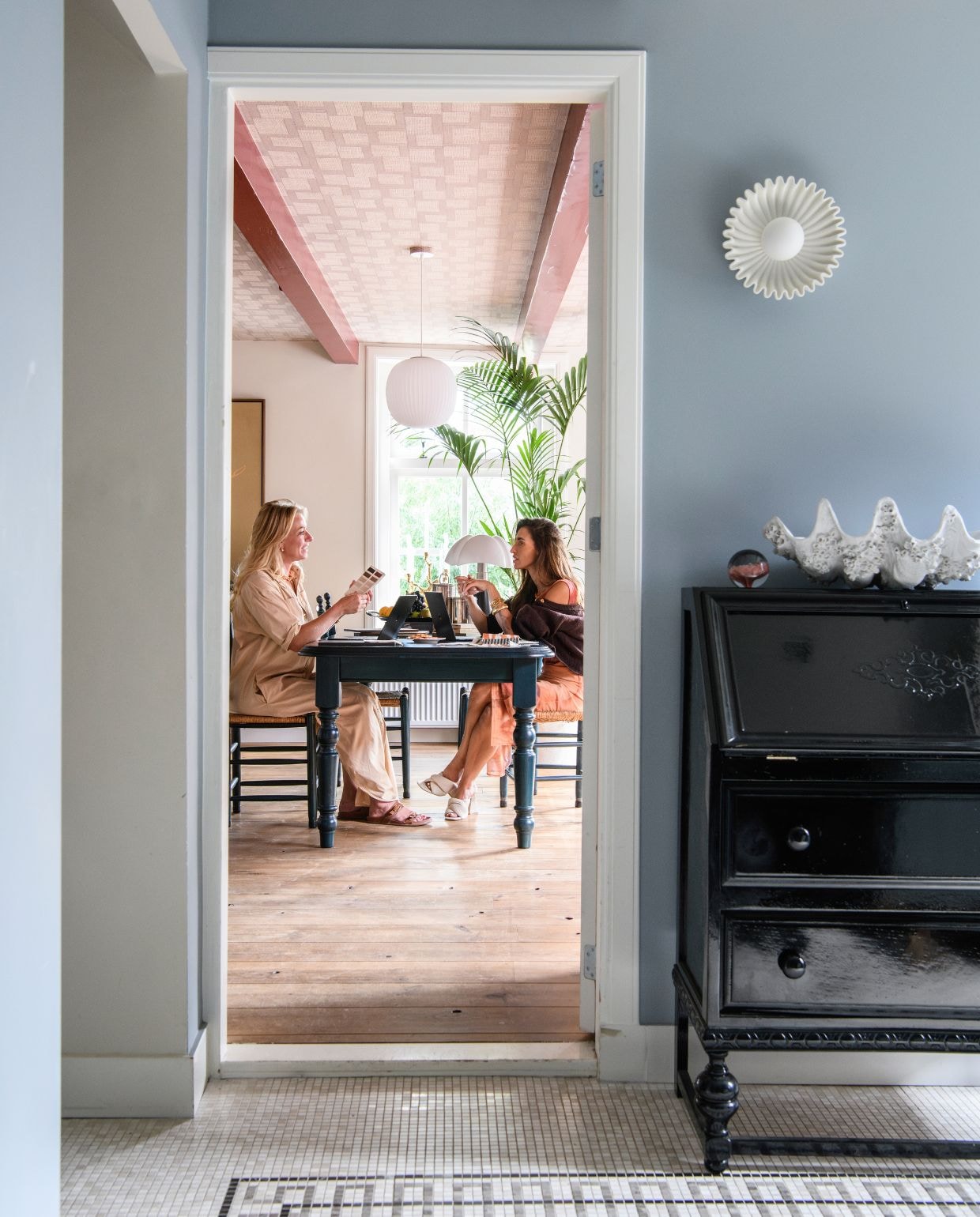 Muurkleur Parma Grey van Farrow & Ball. Muurdecoratie Kwantum. Antiek dressoir via Reliving. Schelp uit Parijs. Mozaïekvloer Bottocino via Designtegels. Houten vloer studio origineel. Kleur balken Lipstick Lover van Lab Paint. Behang plafond Essentials Totem van Arte via Lab Colour the World. Tafel en stoelen kringloop. Tafellamp Pipistrello van Martinelli Luce. Hanglamp Michael Anastassiades. vtwonen 06-2026 | styling Esther Loonstijn | fotografie Louis Lemaire