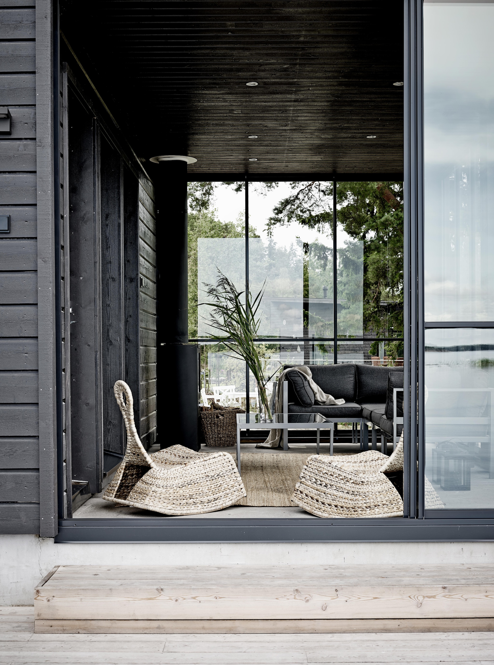 De veranda met houtkachel waardoor je er ook in de herfst en zelfs winter aangenaam kunt zitten. Deze is ingericht als lounge van de sauna. Schommelstoel Ikea. vtwonen Landelijk 08-2026 | fotografie Krista Keltanen | productie Living Inside