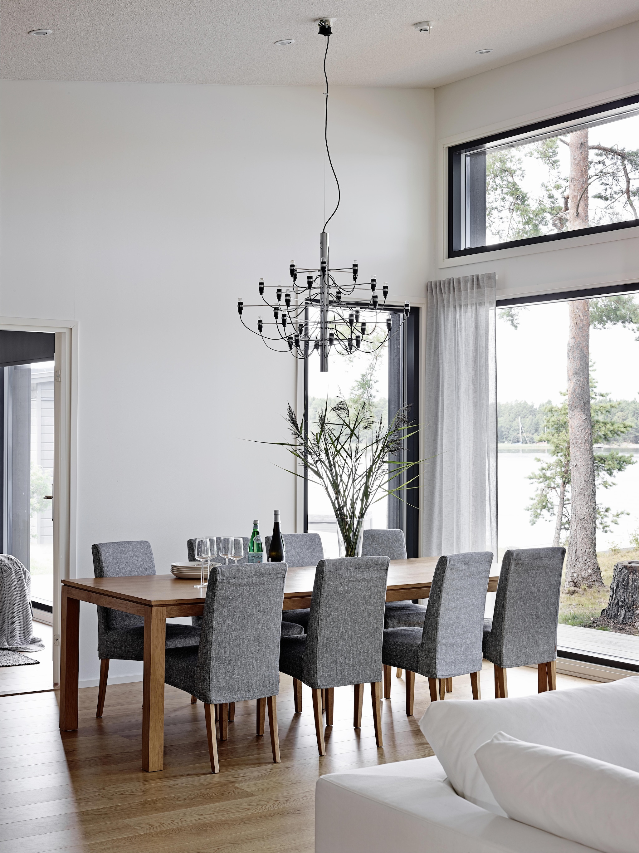 De eikenhouten eettafel en stoelen stonden al in het vorige huis van de familie. De stoelen kregen een nieuwe stoffen hoes van de Finse winkel Maricken. 
Kroonluchter 2097 van Flos. vtwonen Landelijk 08-2026 | fotografie Krista Keltanen | productie Living Inside