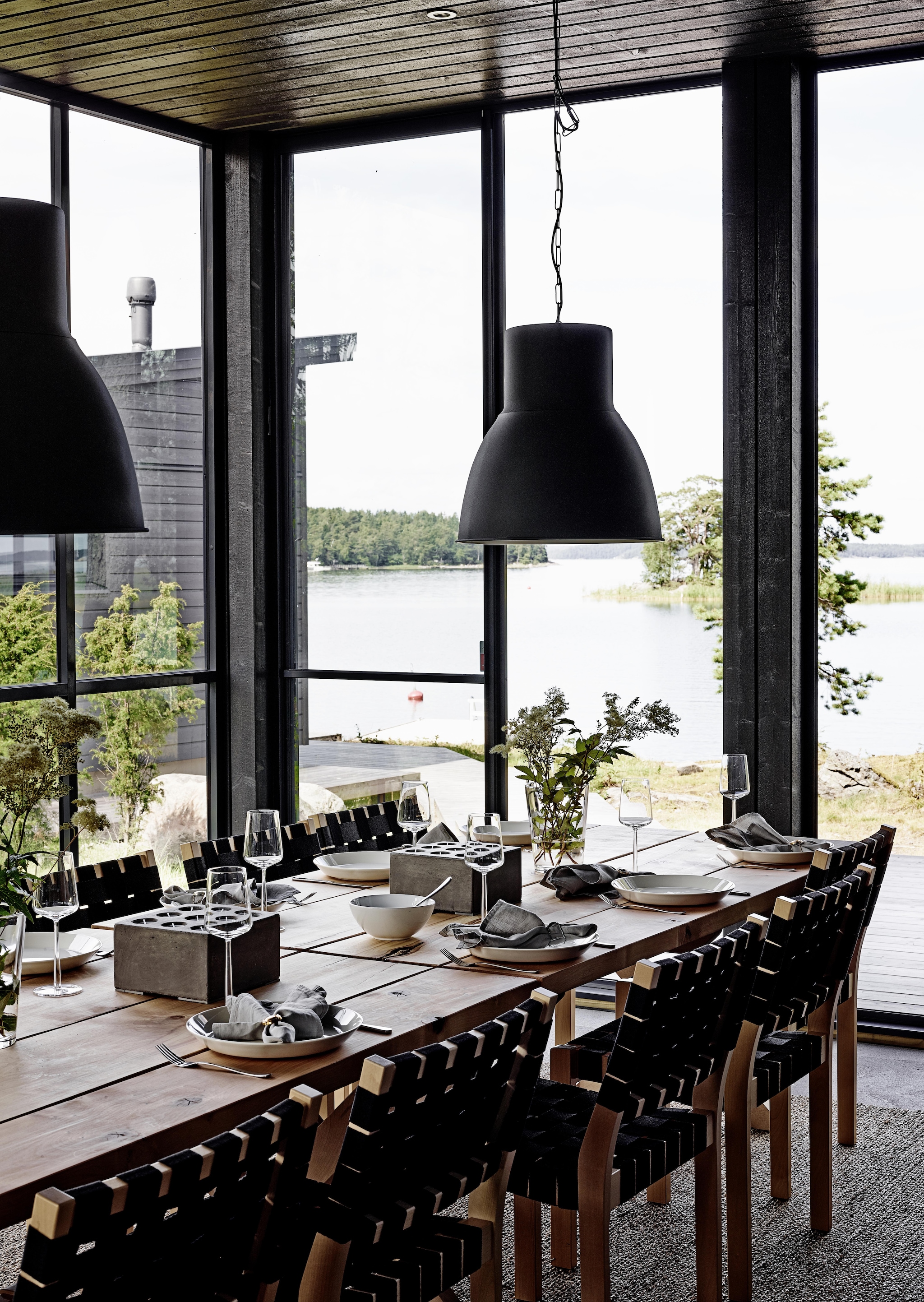 De veranda met terrastafel van onbewerkt berkenhout, gemaakt door een lokale timmerman. Stoelen 611 van Alvar Aalto voor Artek. Lampen Hektar van Ikea. vtwonen Landelijk 08-2026 | fotografie Krista Keltanen | productie Living Inside