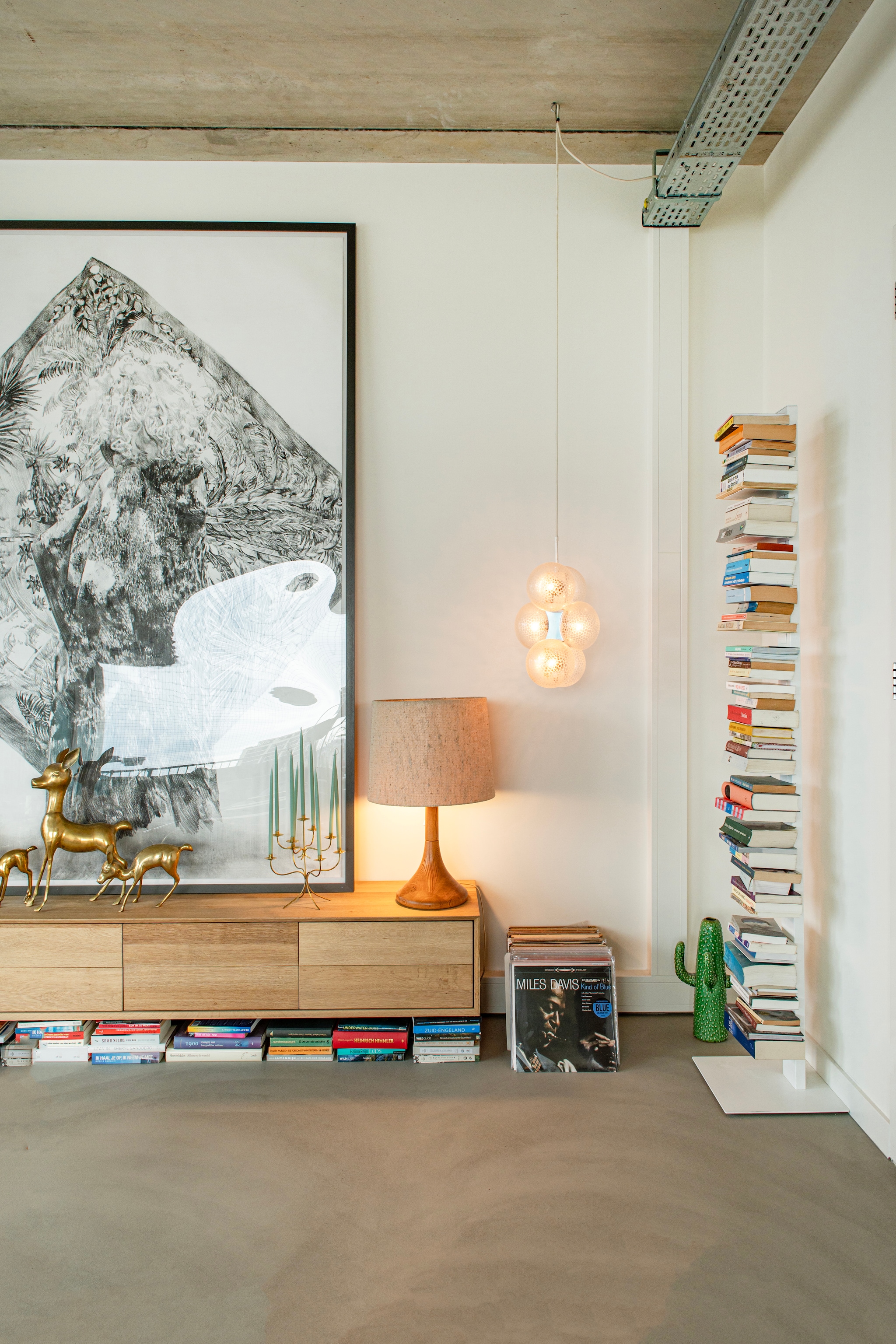 Wandkast Loods 5. Houtskool op doek Anouk Griffioen. Tafellamp Domus, vintage. Hanglamp Sputnik, vintage. Boekenstandaard Sapiens van Bbb Italia. Lavasteen gietvloer Berkers Vloeren. vtwonen 09-2026 | fotografie Caroline Coehorst