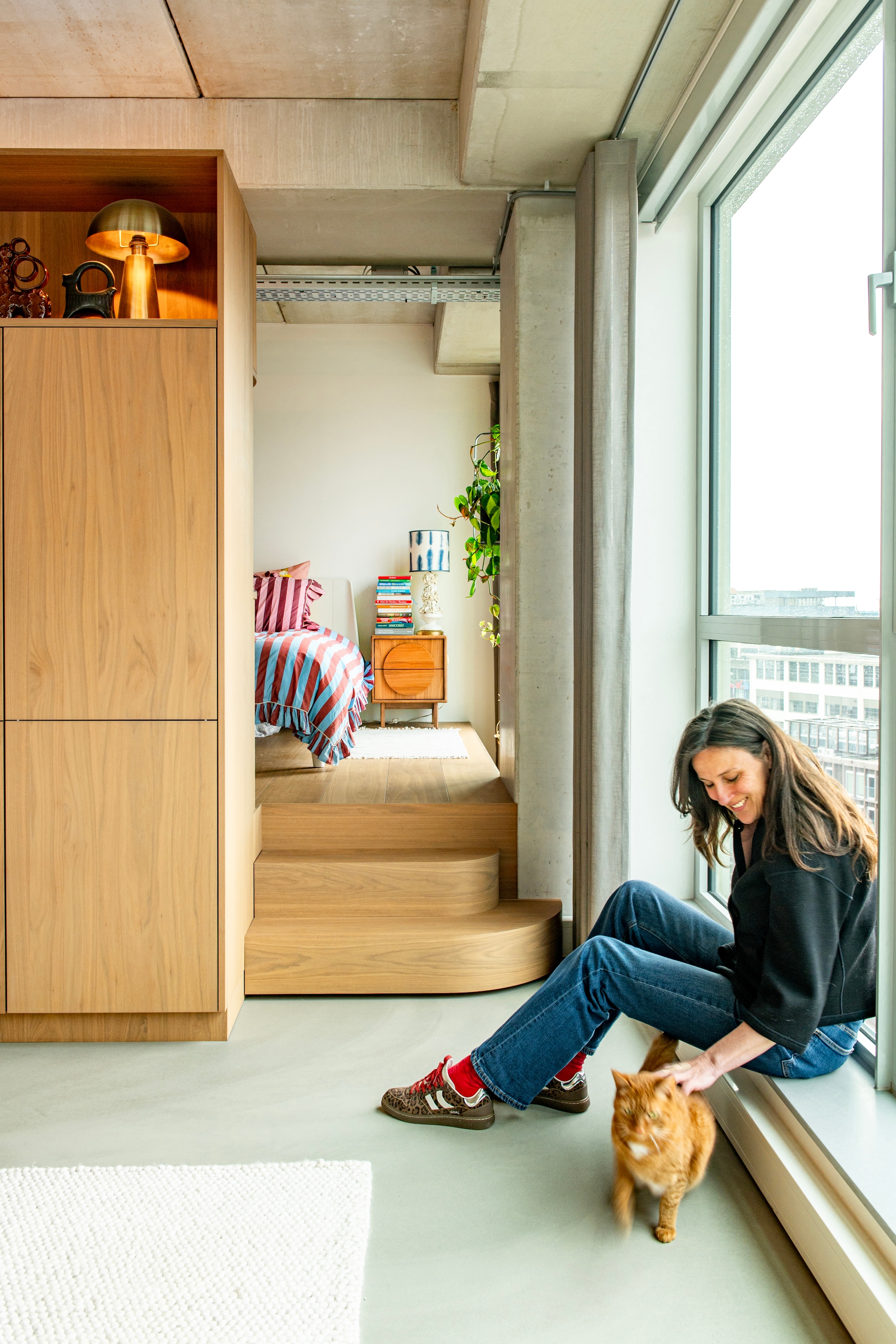 Multifunctioneel meubelblok ontworpen door Vervoort Architecten, uitgevoerd in shinnoki frozen walnut door Vos Interieur. Bed Essential van Auping. Dekbedovertrek Tbco. Nachtkastje Groove van Zuiver. Lampenkap Studio Limonada. Gouden lamp Kwantum. vtwonen 09-2026 | fotografie Caroline Coehorst