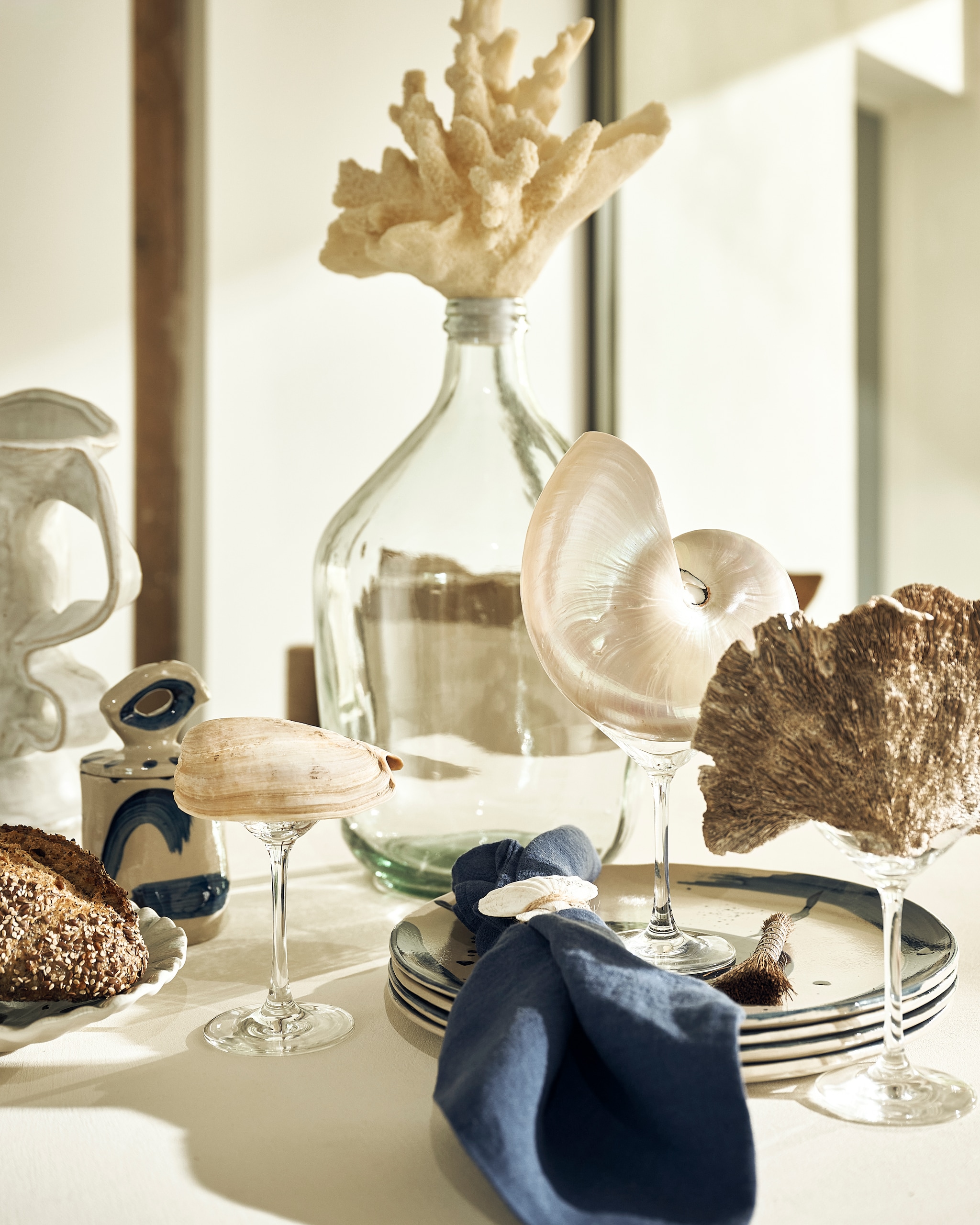 Pebb eettafel, betonlook, shade of linen, 120 cm (Ø) € 1350,- (pebb.nl). Linge Particulier servet, linnen, atlantic blue € 15,-, Jars Céramistes bord Dashi L, céladon € 49,- (couleurlocale.eu). Serax pot Sophia 03, keramiek, beige-blauw € 32,-, dinerbord Sophia, keramiek, beige-blauw, set van 2 € 36,-, vaas Rosie 03, keramiek, wit € 120,- (serax.com). L’etoile Japanse theeroerder, bamboe, naturel € 11,90 (letoile.store). Maisonnl vaas met nepkoraal, glas, wit € 189,- (maisonnl.com). Libeco kussenhoes Julian, linnen, railroad stripe € 113,- (libecohomestores.eu). Overig privébezit. vtwonen landelijk 8-2026 | styling Liza Wassenaar | fotografie Sjoerd Eickmans