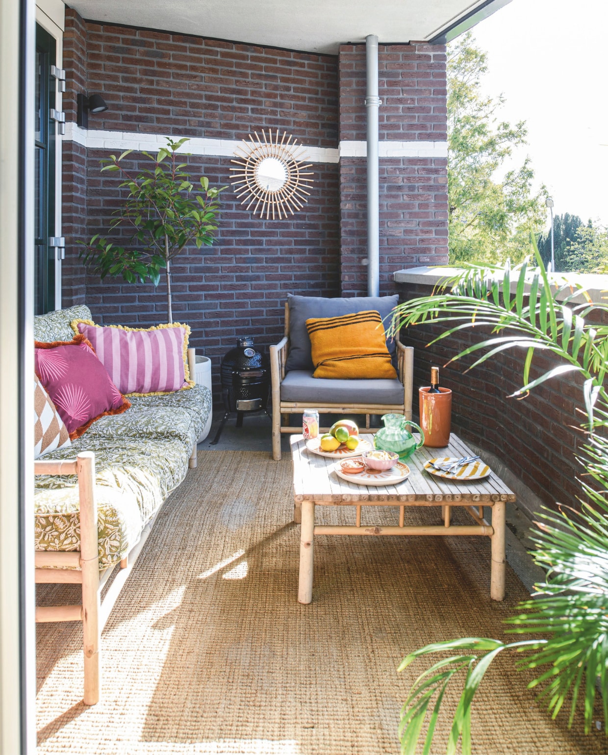Bank, fauteuil, grijze kussens, vloerkleed en salontafel Marktplaats. Loungekussens De Eekhoorn. Oranje sierkussen, spiegel, karaf, borden en wijnkoeler kringloop. Overige kussens Loods5. vtwonen 06-2026 | styling Maaike van Haaster | fotografie Louis Lemaire