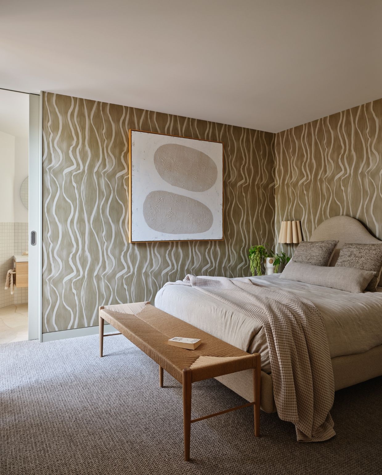 Gastenkamer met maatwerk bed van Create Estate. Behang Luxe Stripe in Khaki van Olive et Oriel. Bank Rj Living. Kunstwerk Middle Of Nowhere. Wandlampen Lighting Collective. vtwonen Design 05-2026 | fotografie Lisa Cohen