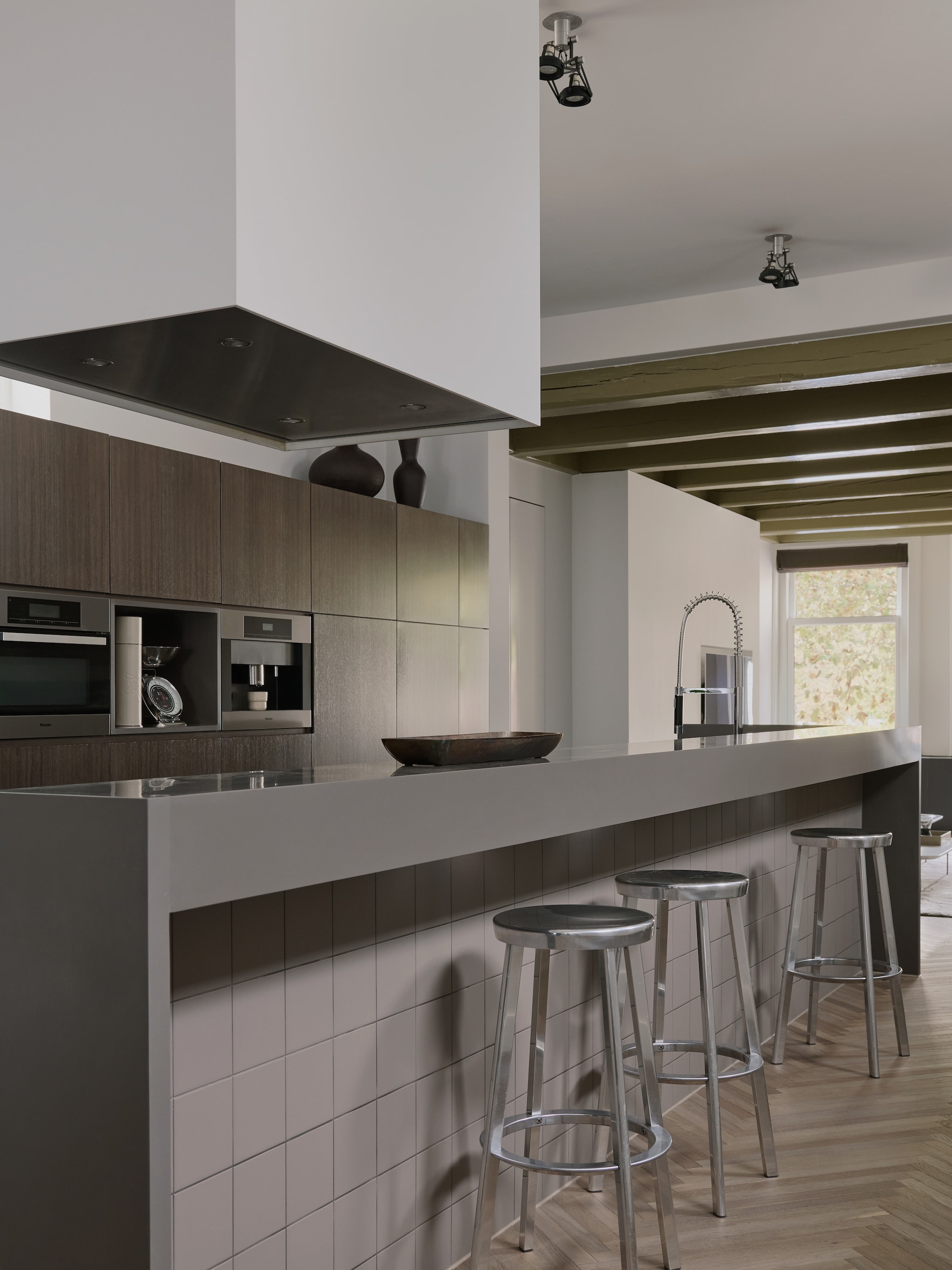 Maatwerk keuken door Peter Vocking. Het eiland is wel vijf meter lang, met delen van Corian en terrazzo, onderdaan tegels van Mosa. Kraan Dornbracht. Aluminium krukken Magis. Plafondspots Modular Lighting Instruments. vtwonen design 7-2026 | fotografie Kasia Gatkowska