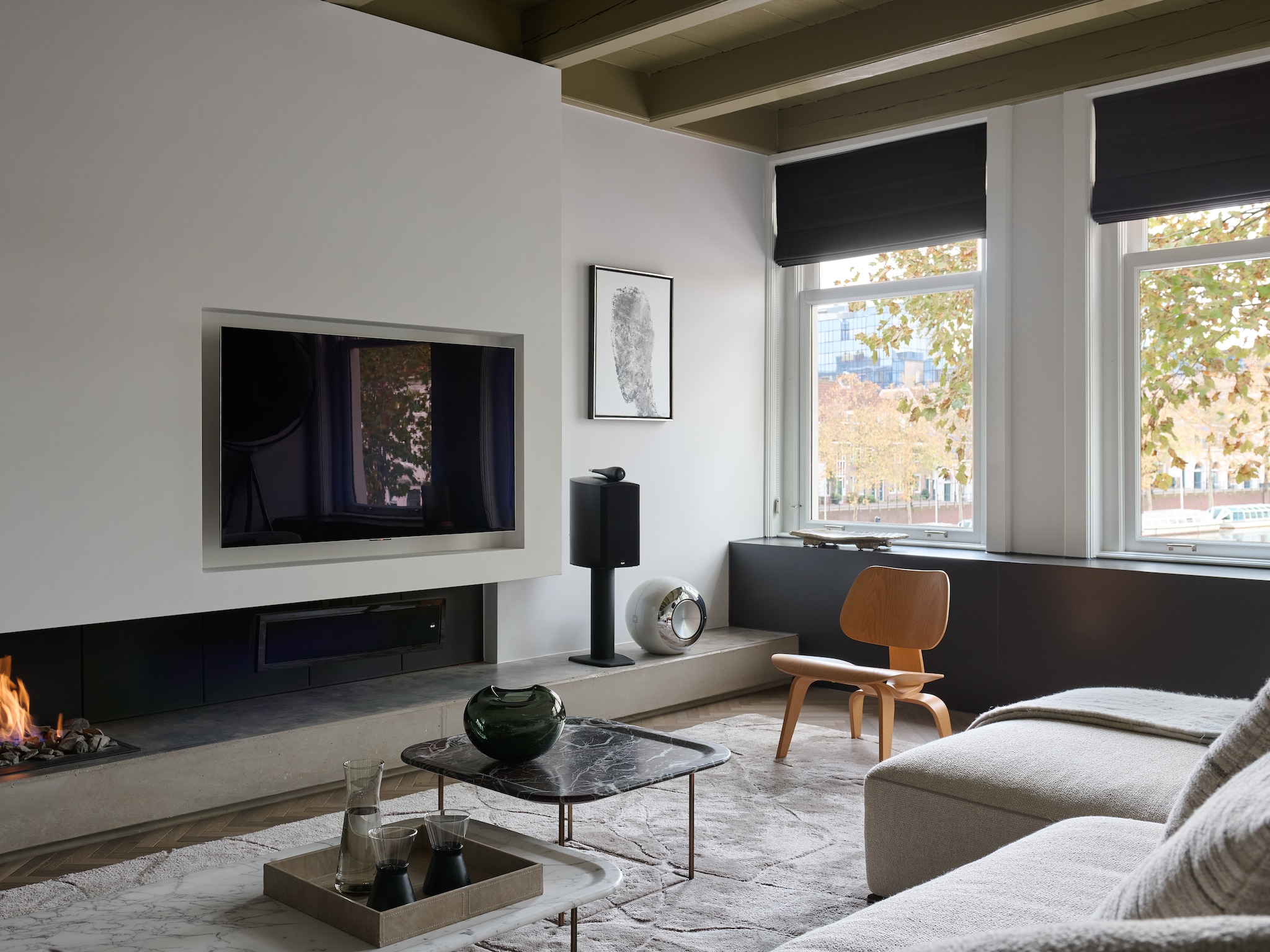 Eiken vloer. Vloerkleed Ozzy van Remy Meijers voor Indivipro. Bank Flexform. Stoel Eames voor Vitra. Bijzettafels maatwerk door Lenarduzzi Natuursteen. Groene vaas Whenobjectswork. Karaf Serax. Olielampen IIttala. Speakers Bowers & Wilkins. Kunstwerk Mart Visser. vtwonen design 7-2026 | fotografie Kasia Gatkowska