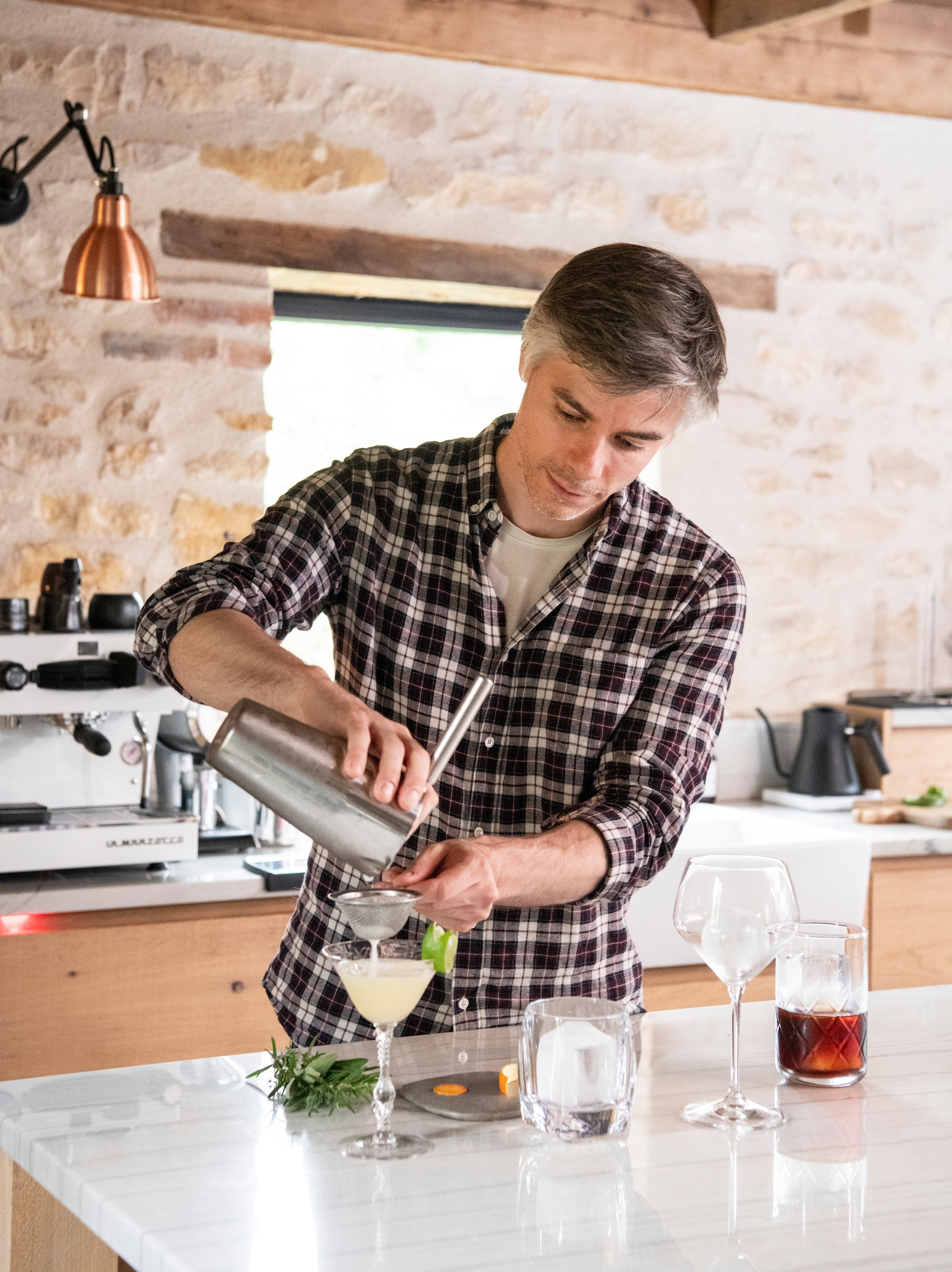 François maakt cocktails voor   de gasten. Koffiemachine   La Marzocco. vtwonen Landelijk 09-2026 | styling Inge van Lieshout | fotografie Louis Lemaire | productie Insidehomepage