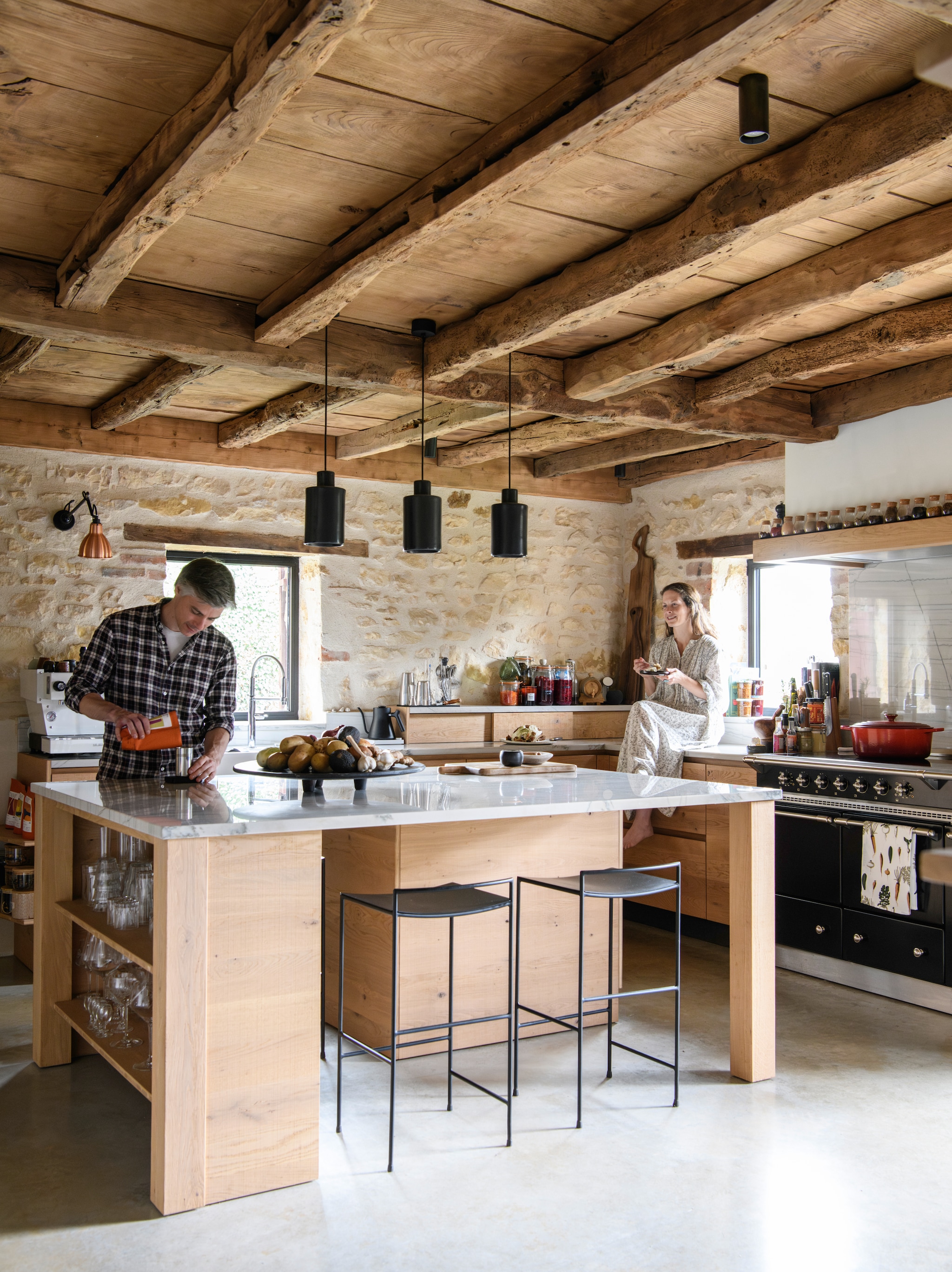 Keuken ontwerp van Kelly en François, gemaakt door een lokale timmerman. Kasten  van eikenhout. Granieten  aanrechtblad van Sensa in kleur white macaubas via Cosentino. Fornuis Lacanche. 
Hanglampen David Pompa. Koperen wandlamp Dcw  
Editions. Spot Koen Van  Guijze voor Serax. Barstoelen Antonino Sciortino voor Serax. Pan Le Creuset. vtwonen Landelijk 09-2026 | styling Inge van Lieshout | fotografie Louis Lemaire | productie Insidehomepage