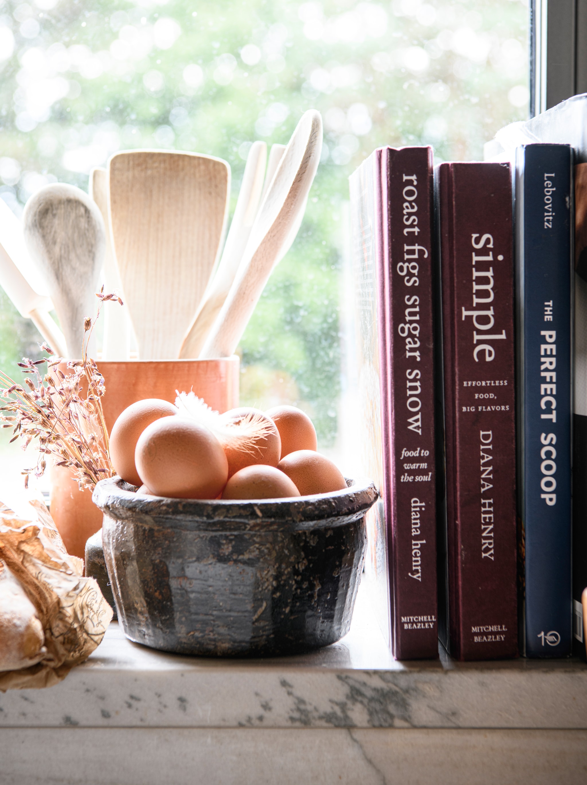 Zwarte schaal Atmosphère D’Ailleurs. Houten pollepels verzamelde Kelly uit kleine winkels tijdens haar reizen. vtwonen Landelijk 09-2026 | styling Inge van Lieshout | fotografie Louis Lemaire | productie Insidehomepage