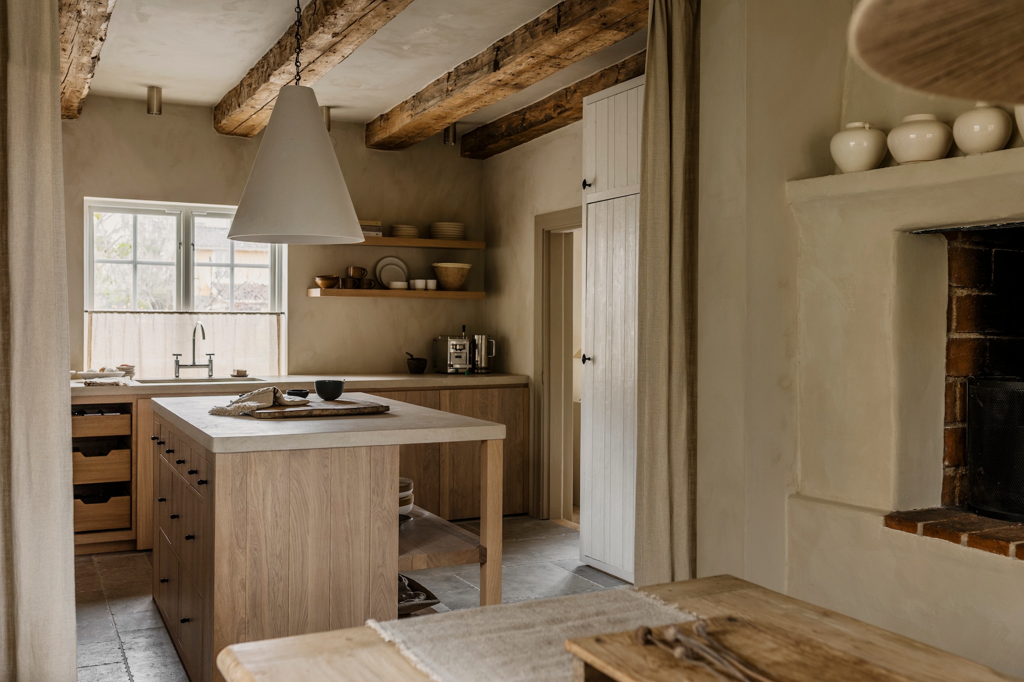 Keuken in eikenhout van Lidhults. Aanrechtbladen in Claystone door Creative Coatings. Hanglamp Rose Uniacke. Zelliges en stenen vloer Stiltje. Handgemaakte keramieken schalen en kopjes uit Laos via Noy Road. Theedoek Libeco. Vintage potten, schalen en porselein Bergenströms Rekvisita. Gordijn via B.a. Studio. De plafondbalken zijn origineel. vtwonen landelijk 9-2026 | Styling Mari Strenghielm | Fotografie Lina Ostling
