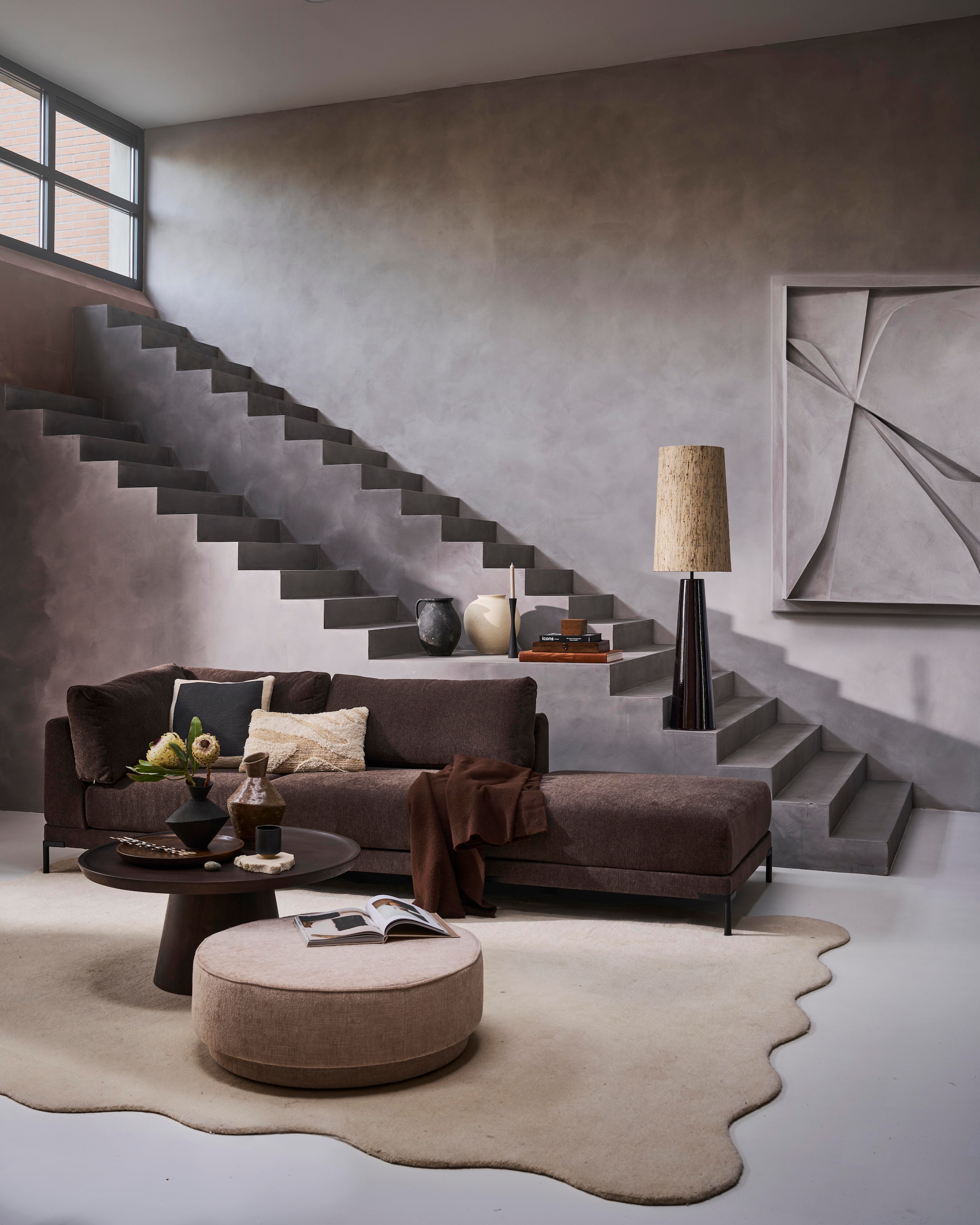 Elementenbank Couple lounge-element links (•4) in chocoladebruin, 200x100x89 cm (bxdxh) € 1399,-. Mangohouten salontafel Coffee A Gogo (•6) in walnootfineer, 90x40 cm (Øxh) € 499,-. Polyester poef Pearl XL (•5) in naturel melange, 80x28 cm (Øxh) € 199,-, verkrijgbaar in meerdere stoffen. Metalen kandelaar in matzwart, vanaf 16 cm (h) € 16,95.M.m.v. artinreturn.nl (schilderij), thefarm-shop.nl (verf muur Bold Basalt, verf trap Consious Concrete), zarahome.nl (vazen op tafel), layeredinterior.com (vloerkleed Scallop), vtwonen.nl/shop (lamp en lampenkap van HKliving). Overig privébezit. vtwonen 10-2024 | styling Cleo Scheulderman | fotografie Jeroen van der Spek