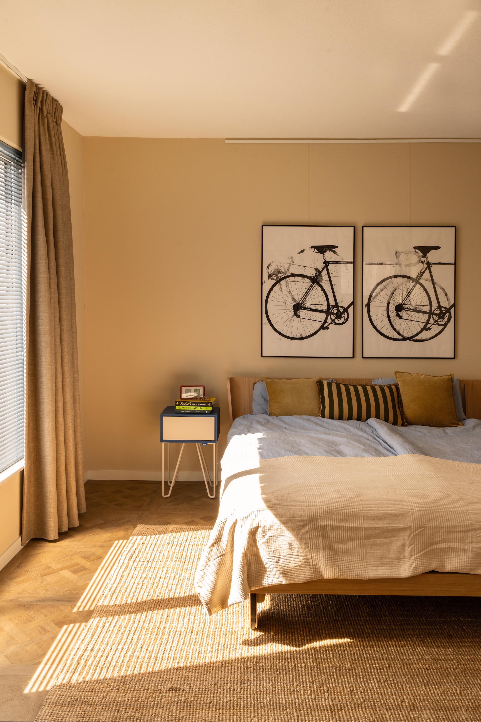 Bed Noa en nachtkastje Pixel van Auping. Kunst Jolly Good Fellow. Vloerkleed Strög van Ikea. Beddengoed Hema. Kussens Loods 5. Muurkleur Joa’s White van Farrow & Ball. Jaloezieën Allure en gordijn Maddison Night Linnen vmasng14 van Veneta. vtwonen 09-2026 | fotografie Lotte van Uittert