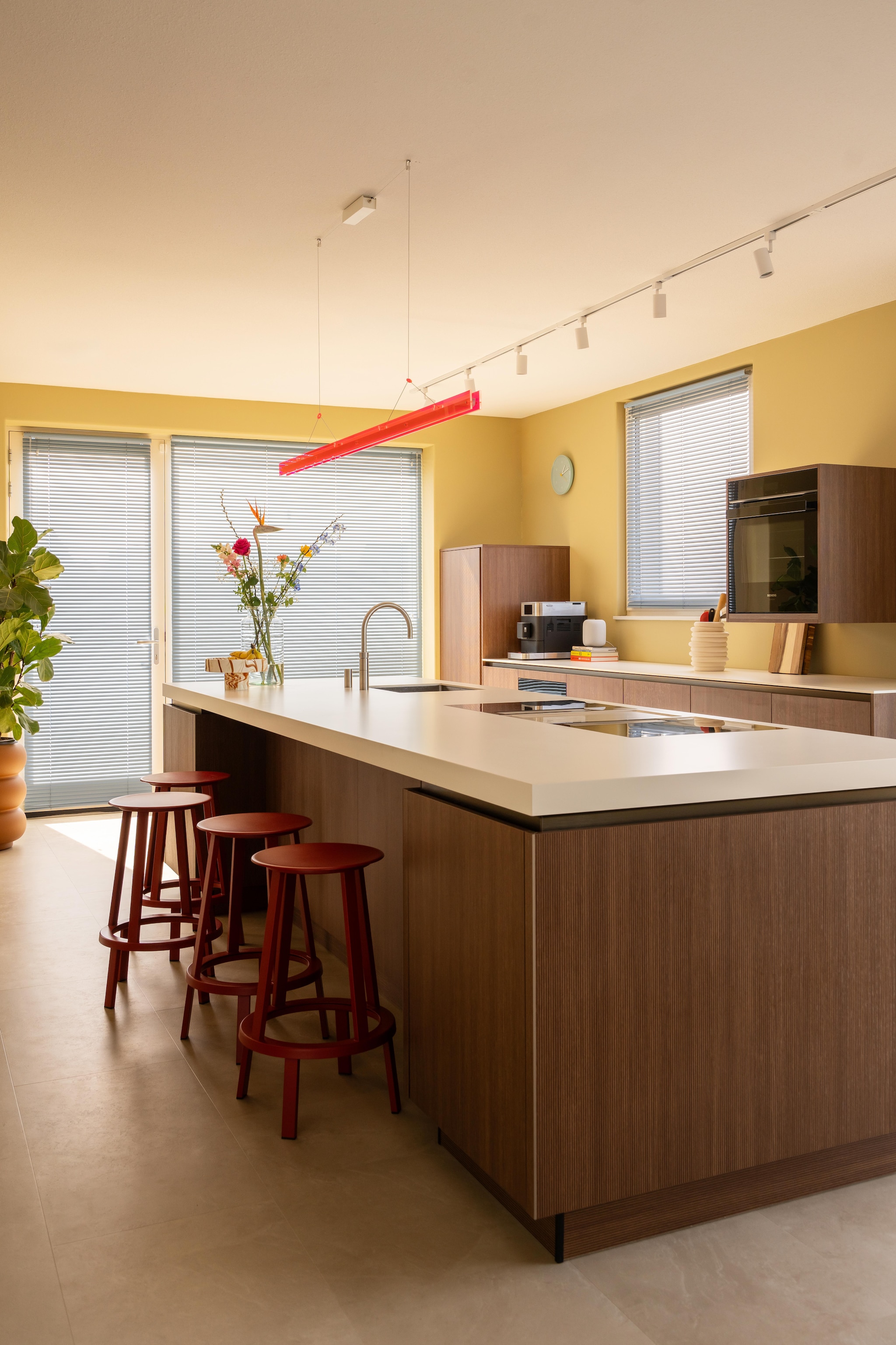 Keuken Mandemakers. Kraan Quooker. Vloer Stanmore dryback beige van Floorlife. Klok en rode barkrukken Revolver van Hay. Oranje lamp Bridge van Tonone. Kookplaat Bora. Oven Siemens. Aluminium jaloezieën Allure in Baby Blue van Veneta. Muurkleur Wild Wonder van Flexa. Plant Intratuin. Pot Elho. Koffiezetapparaat Kitchenaid. Snijplanken Ikea. Pot voor keukengerei Kwantum. vtwonen 09-2026 | fotografie Lotte van Uittert