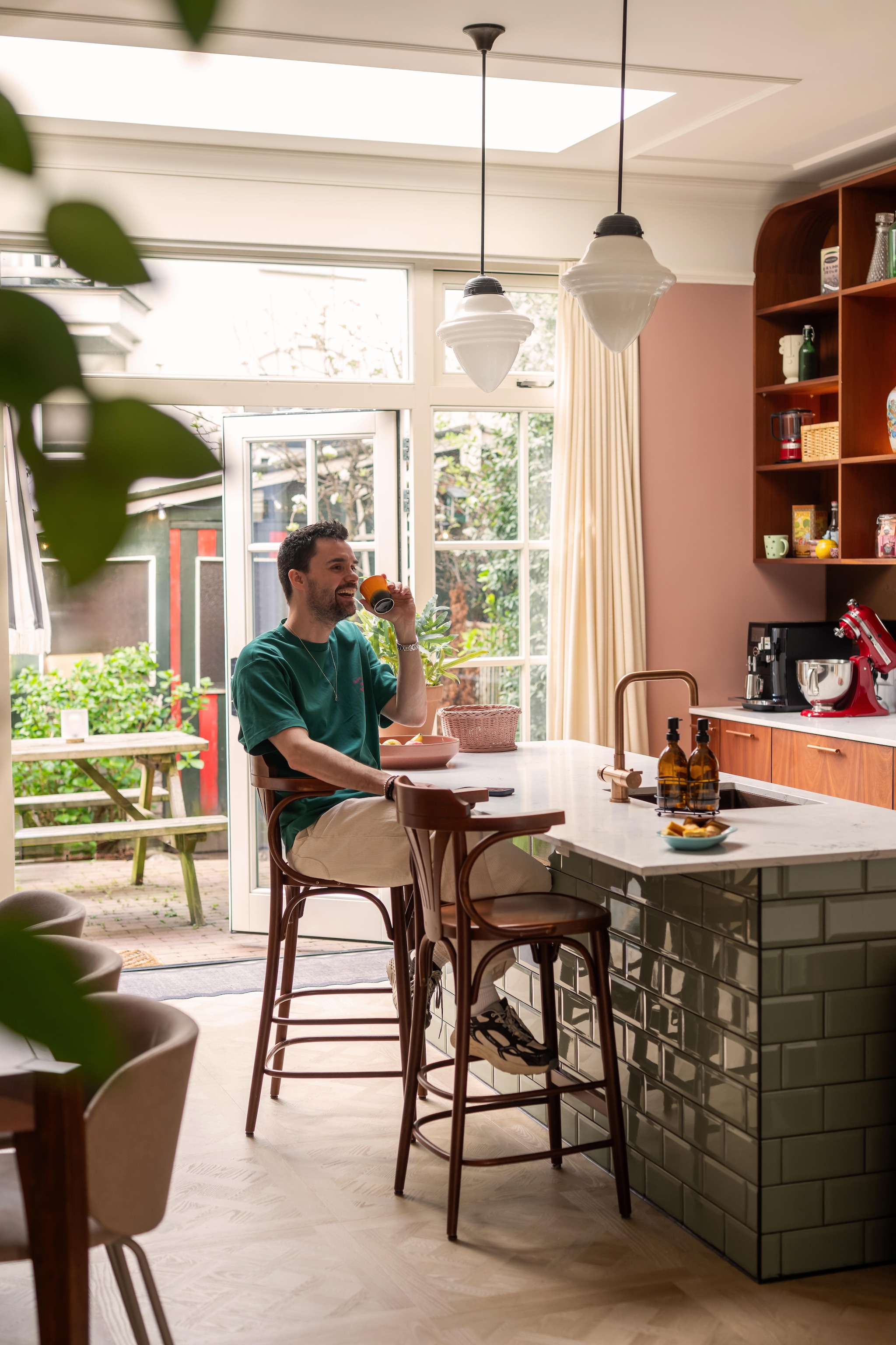 Maatwerkkeuken met kwartscomposiet werkblad en maatwerk in mahoniehout Schaalwerk. Metrotegels in jade groen van Tegels in Huis. Barkruk vintage. Vintage hanglamp uit bar. Koperen kraan Selsiuz. vtwonen 09-2026 | fotografie Lotte van Uittert