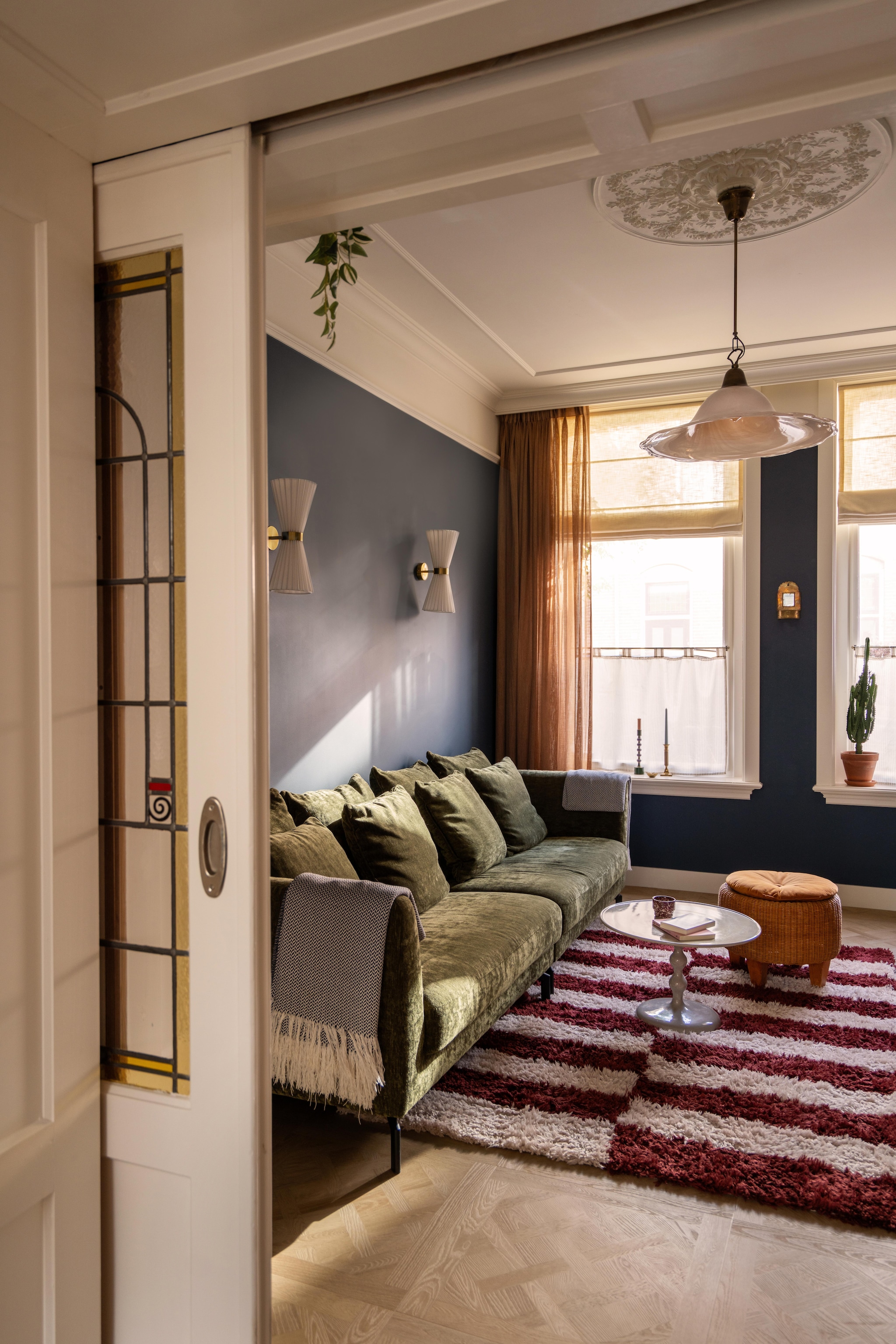 Vloerkleed Block van Loods 5. Wandlampen Telang van Beliani. Bank Homestock. Salontafel Table basse ronde Leen Bakker. Hanglamp en poef kringloopwinkel. Verfkleur Stiffkey Blue van Farrow & Ball. Rozet en sierlijsten Het Schippertje. vtwonen 09-2026 | fotografie Lotte van Uittert