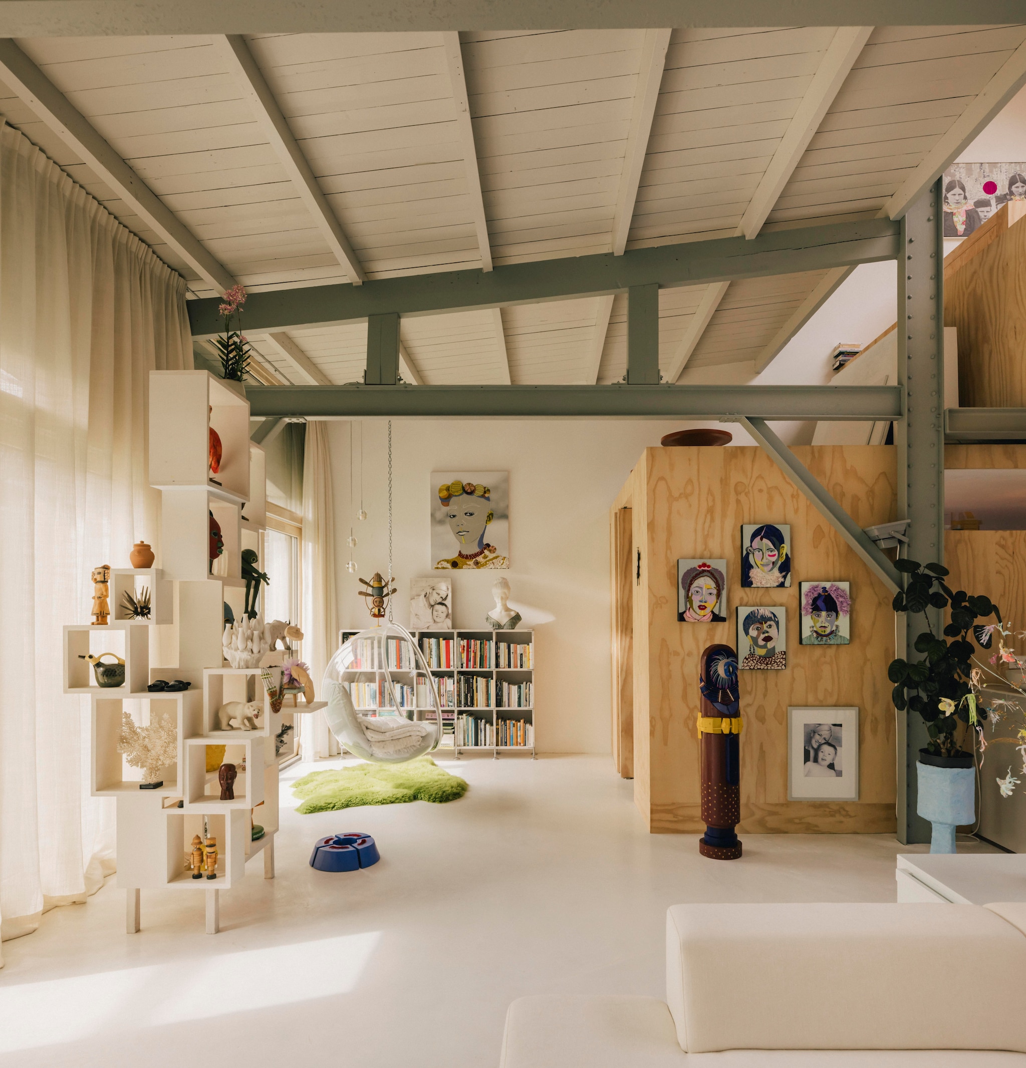 Plankenkast zelfgemaakt. Hangstoel Bubble van Eero Aarnio. Kunstwerken aan houten wand uit de serie #Headdress en totempaal ChuckacaBa van Preta Wolzak. vtwonen design 7-2026 | fotografie Katoo Peeters
