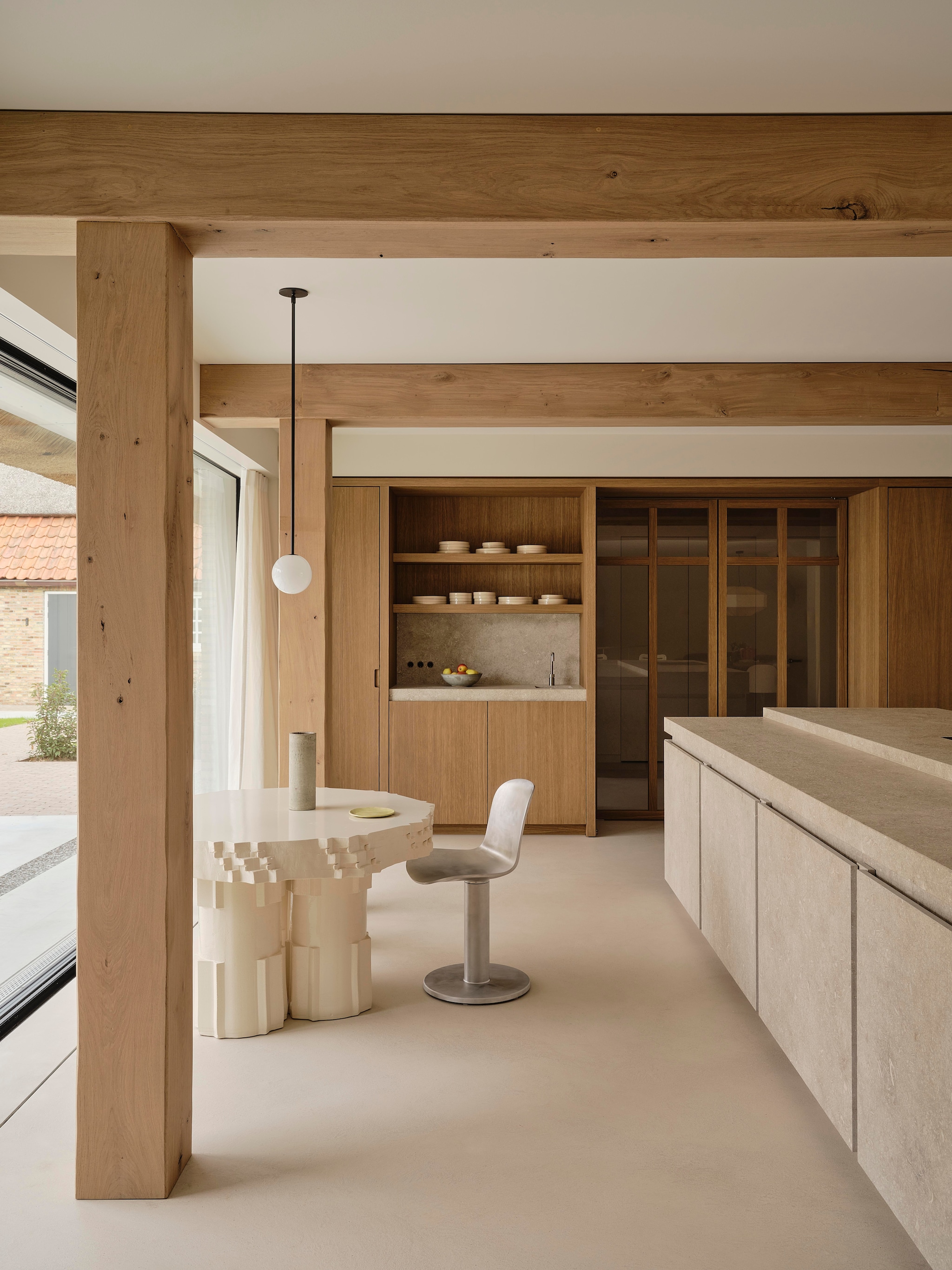 Keukeneiland gemaakt van Portugese natuursteen in geometrische vormen. Vloer microcement. Stalen balken bekleed met houtfineer waarvoor een unieke beitskleur is ontwikkeld. vtwonen design 8-2026 | fotografie Space Content Studio