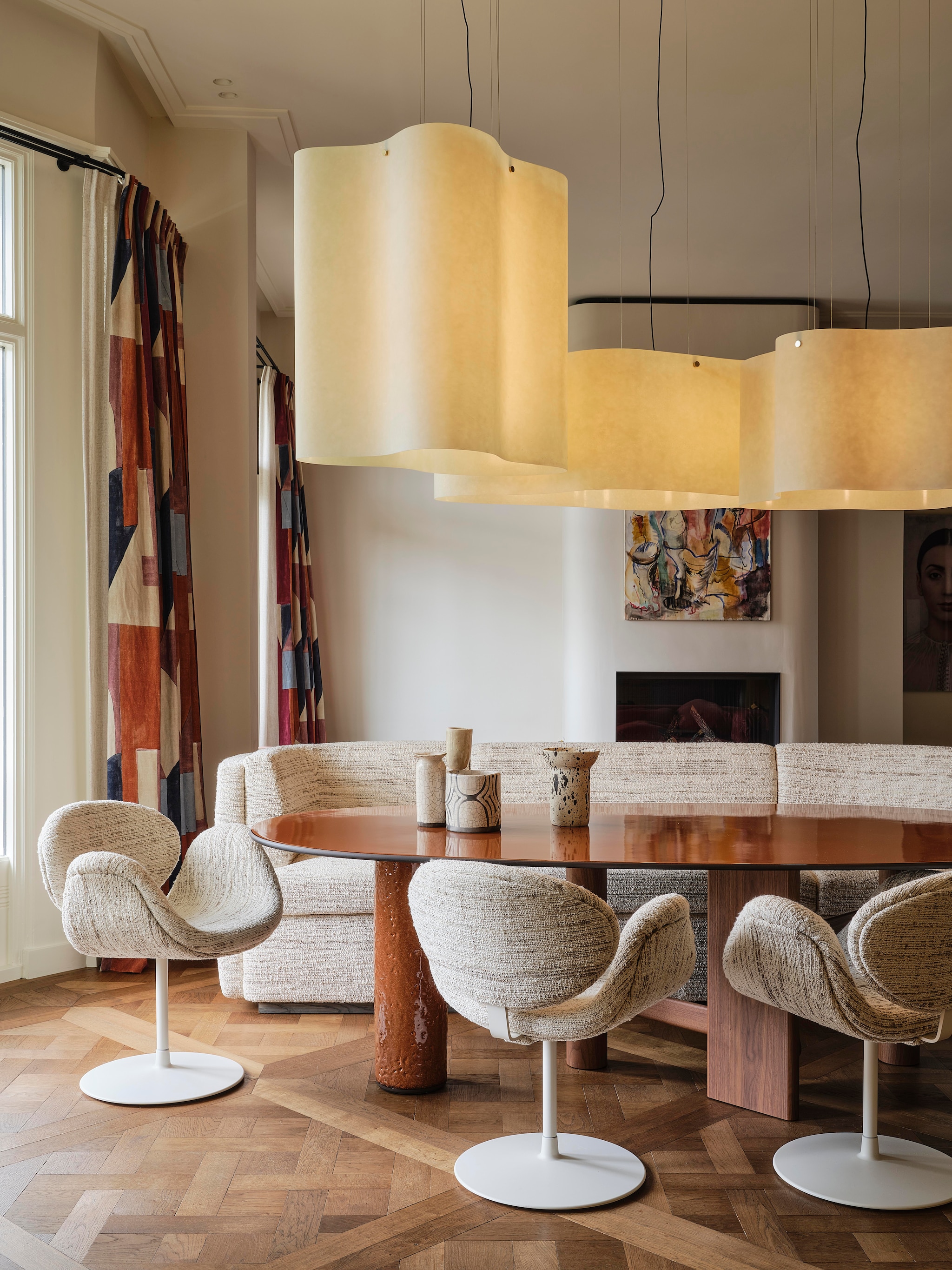 Gordijnen District Claret van Kelly Wearstler via Mcveer Collections. Tafel Sengu van Cassina via Edha Interieur. Bank maatwerk Linteloo via Edha Interieur, met stof Clay Kaduna van Larsen. Stoelen Artifort, met stof Clay Kaduna van Larsen. Keramiek op tafel Mel Lennon via Atelier ND Interior. Kunstwerk boven schouw Niek de Vriendt. Haard ontworpen door Atelier ND Interior en gerealiseerd door Jos Harm. Muur behandeld met stucco-verf in kleur Saint-Tropez van Wow Makers. Lampen Nuvola van Draga & Aurel via Baxter.