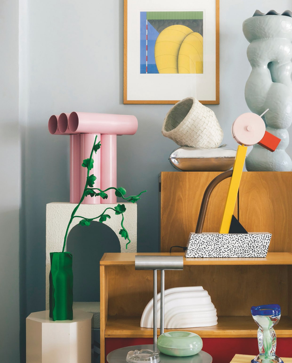 V.l.n.r. Groene Feltplant Blossom van Wandschappen. Roze kruk Septem van Axel Chay. Lamp Tahiti van Memphis Milano. Witte wandplank van David Derksen x Cor Unum. Glasobject The Ocean Cup van Sandra Keja Planken. Werk aan wand Marinus Fuit. Kast Cu3 van Pastoe. Metalen kussen van Emma Stocklassa voor Hem X. Vaas Vahe Ensemble. Bijzettafel Impose high van Handmade Industrials. Kast Db51 van Pastoe. Stoel C1513 van Daniel Stegen. Opberger Mini-donut Sabine Marcelis x Ikea. Asbak matglas ss Normandie French Line.
