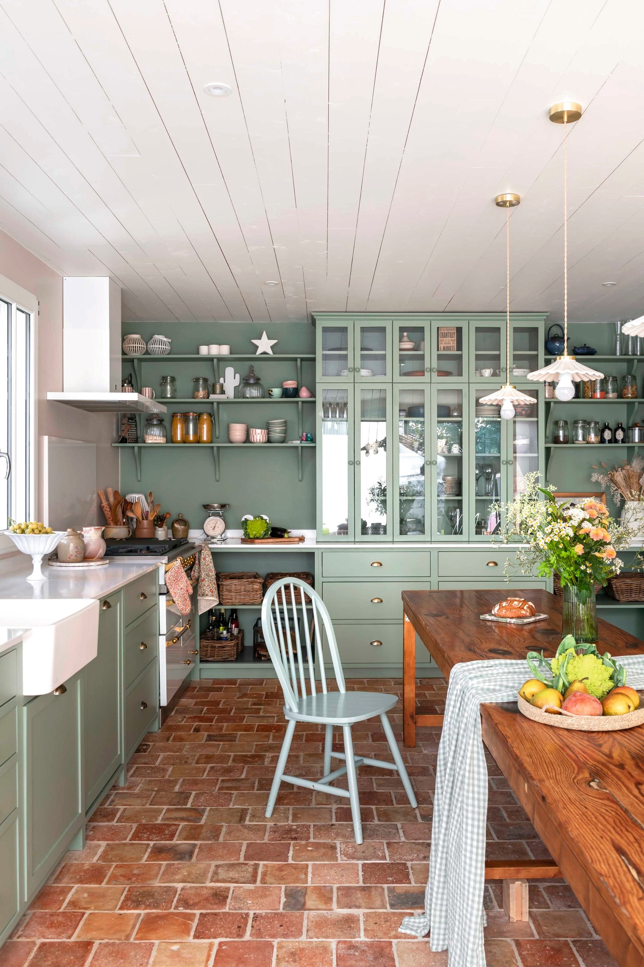 Keuken maatwerk door lokale meubelmaker Pia Île de Ré. Wand- en hanglampen Cyrillus. Tafel Selency. Stoelen La Redoute. Wasbak Villeroy & Boch. Fornuis Lacanche. Vaas HKliving. Fruitmand Monoprix. Vergelijkbare terracotta plavuizen Piet Jonker. Kleur keuken Windmill Lane van Little Greene. Wandkleur Argile de Moneteau van Argile Peinture.