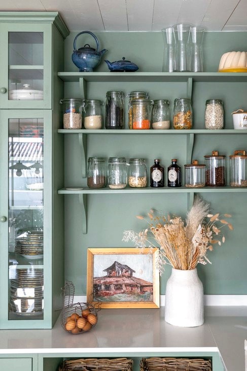 Keuken maatwerk door lokale meubelmaker Pia Île de Ré. Wand- en hanglampen Cyrillus. Tafel Selency. Stoelen La Redoute. Wasbak Villeroy & Boch. Fornuis Lacanche. Vaas HKliving. Fruitmand Monoprix. Vergelijkbare terracotta plavuizen Piet Jonker. Kleur keuken Windmill Lane van Little Greene. Wandkleur Argile de Moneteau van Argile Peinture. vtwonen Landelijk 6-2026 | styling Amandine Berthon | fotografie Julien Fernandez