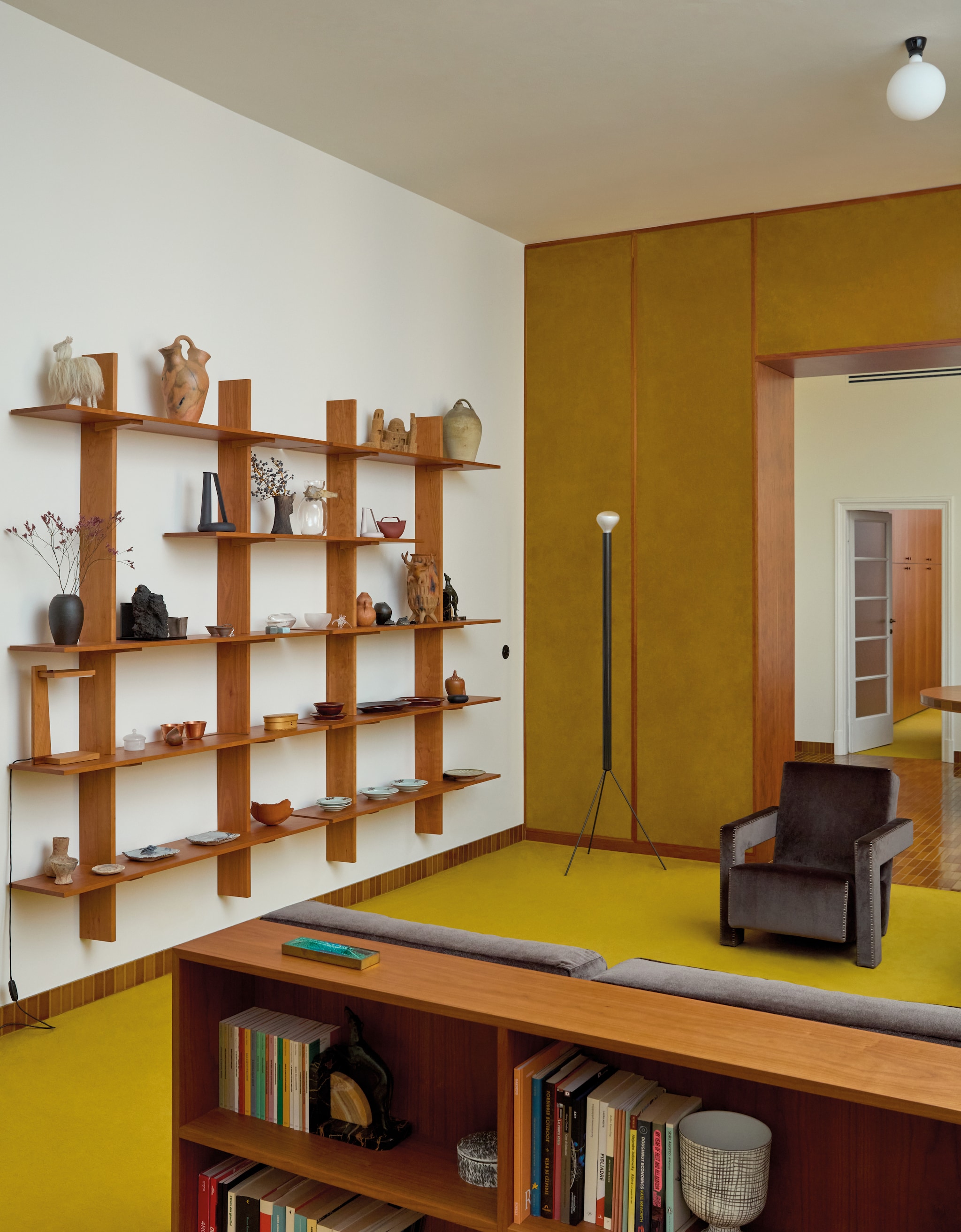 Bruine Utrecht fauteuil Gerrit Rietveld voor Cassina. Staande lamp Achille & Pier Giacomo Castiglioni voor Flos. Houten wandkast Formafantasma. Diverse objecten in kast eigen ontwerpen Formafantasma en vondsten uit Japan, Mexico, Korea en Noord-Afrika. Bruine bank met boekenkast Formafantasma voor Disé. vtwonen design 8-2026 | fotografie Chiara Quadri