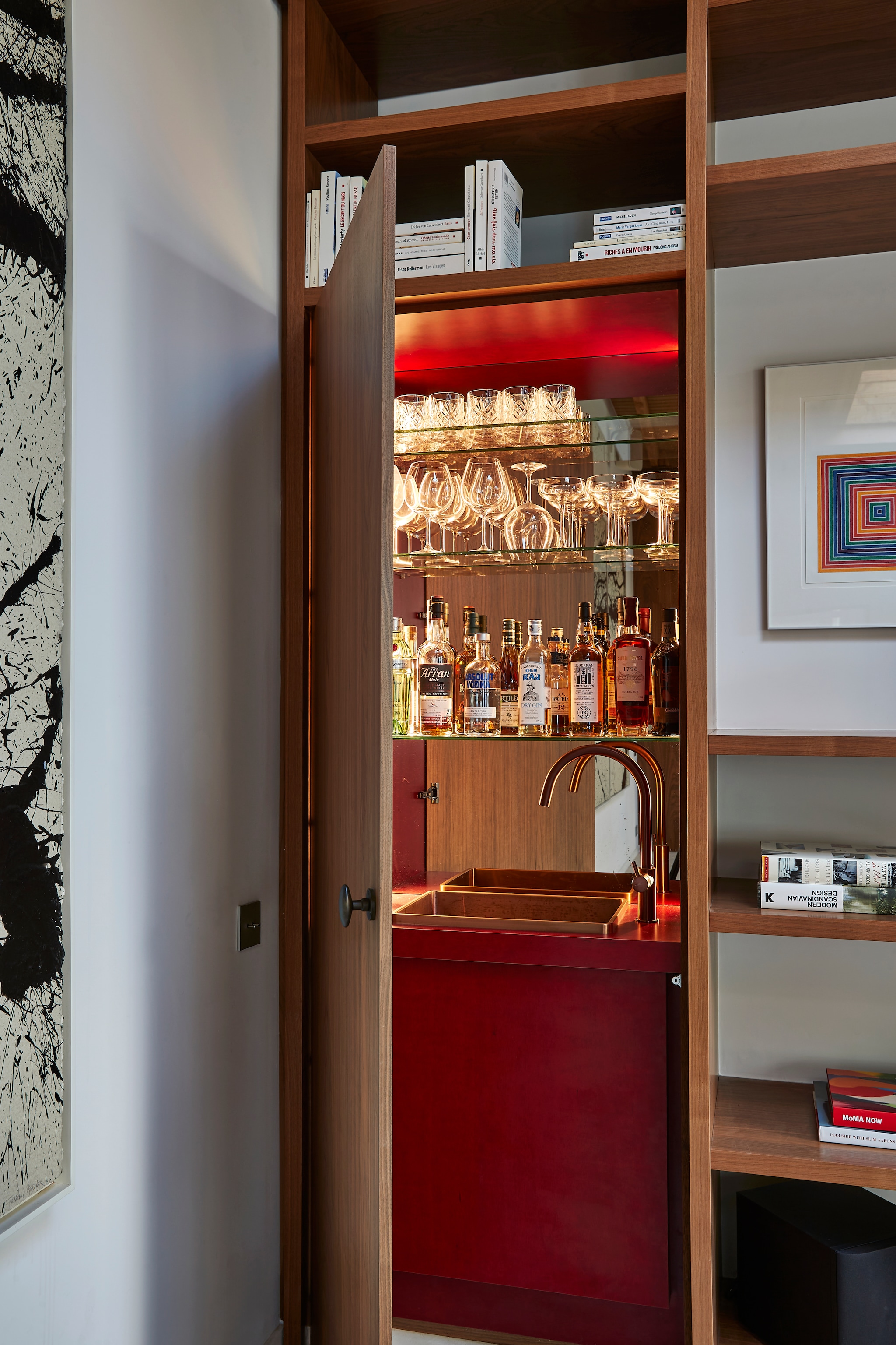 Verborgen bar in de bibliotheekwand met rood gelakt hout. vtwonen design 8-2026 | productie living inside | fotografie jan verlinde