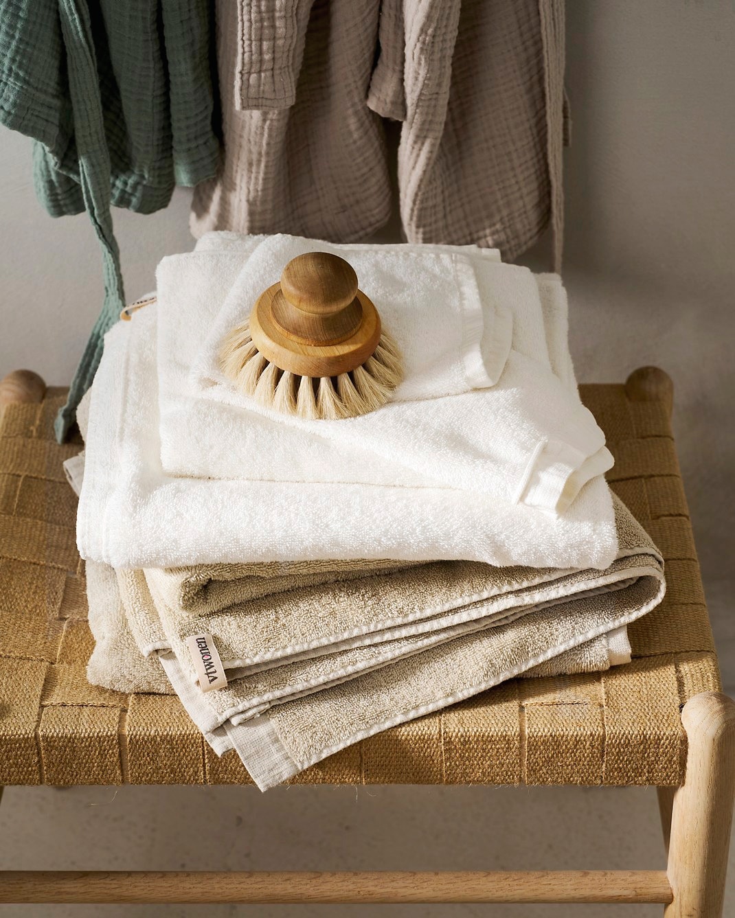 vtwonen handdoek Soft Embrace, katoenfluweel, zand en wit, 30x50 cm € 7,95, 50x100 cm € 10,95 en 70x140 cm € 17,95, vtwonen badjas Gentle Embrace, katoen mousseline, zand en saliegroen, S/M en L/XL € 49,95. Overig privébezit. vtwonen collectie 7-2026 | styling Cleo Scheulderman | fotografie Jeroen van der Spek