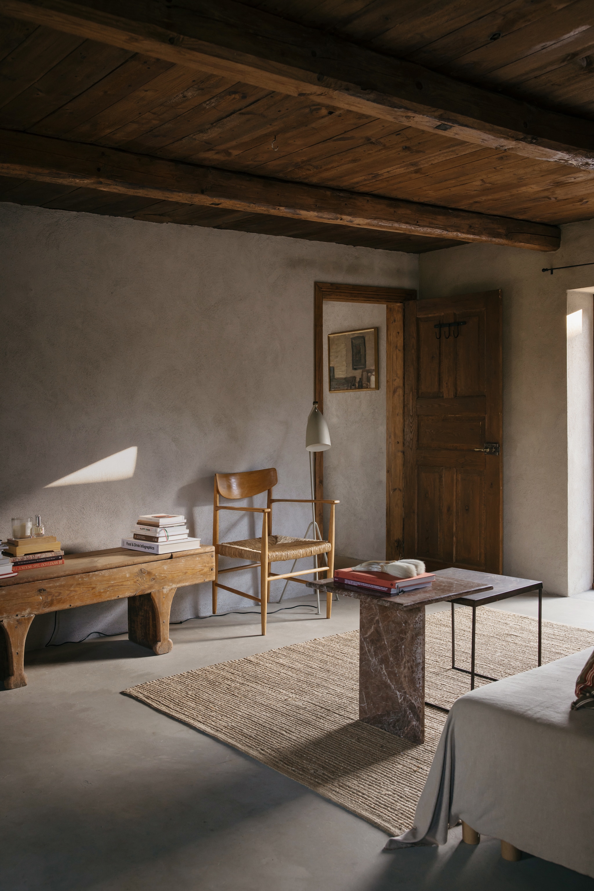 De woonkamer van het gastenverblijf. Oude Zweedse boerderijbank. Vintage stoel van Børge Mogensen. Vloerlamp Grasshopper van Greta Grossman. Marmeren tafel vintage. vtwonen Landelijk 10-2026 | Styling Karolina Vertus | Fotografie Isabell N Wedin | Productie Living Inside
