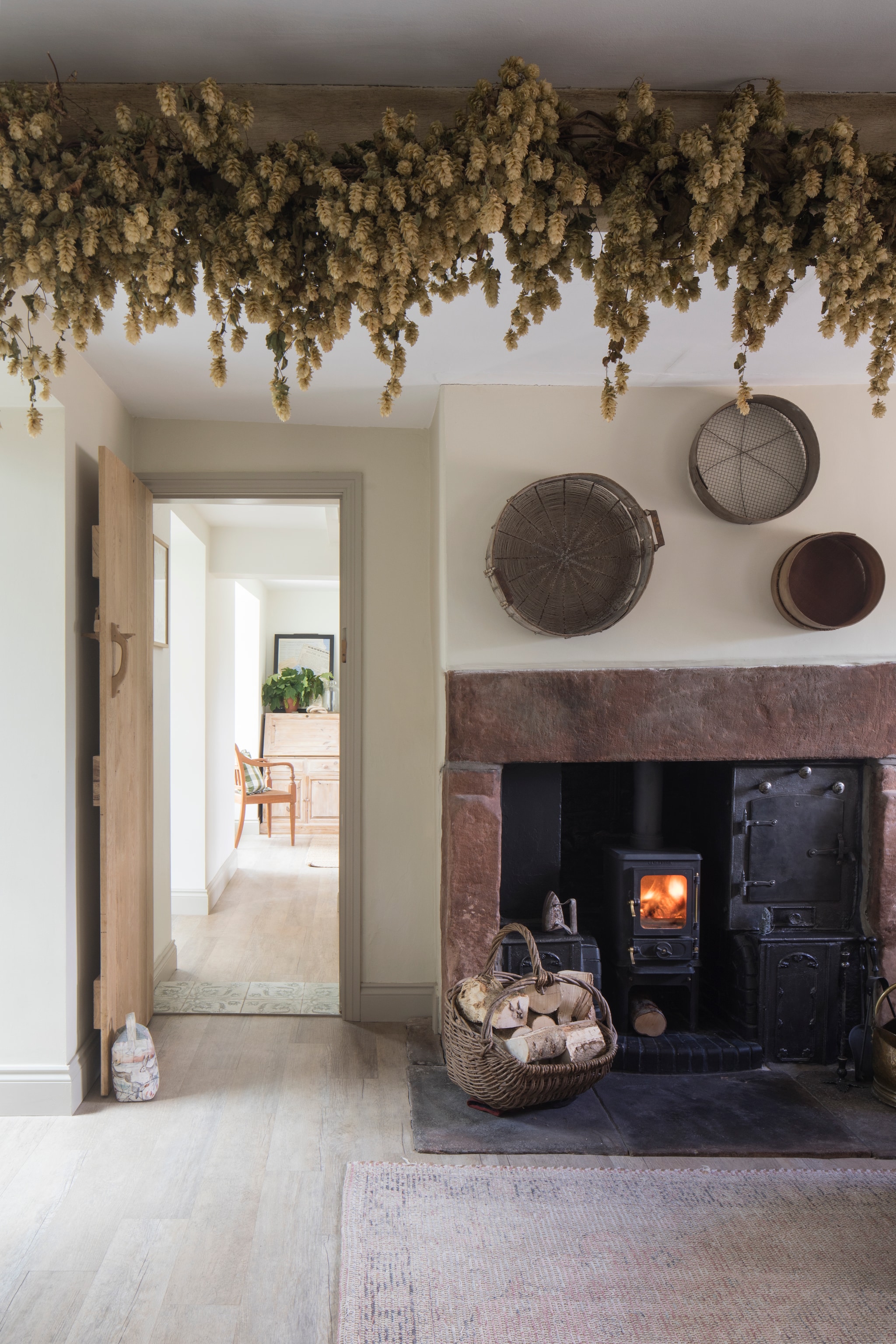 Muren in Lime White van Farrow & Ball. Gedroogde hop van Castle Farm. Manden boven haard antiek, soortgelijk Combitex. Vloer Karndean Coastline Oak. Secretaire tweedehands. vtwonen Landelijk 10-2026 | styling Marisha Taylor | fotografie James French | productie Living Inside