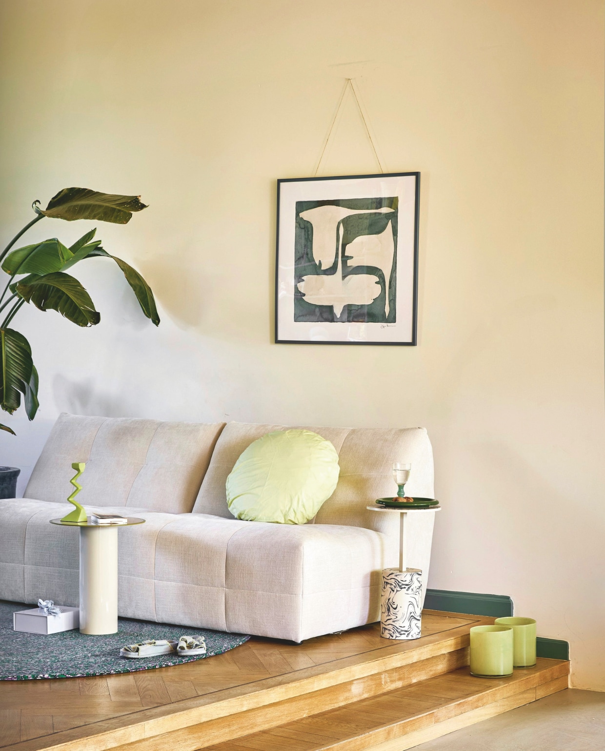 By Sidde bank Molli, polyester, calm beige, 204x102x78 cm (bxdxh) € 1498,- (bysidde.com). Urban Nature Culture bijzettafel Tiro, ijzer, almond milk, 36x42,5 cm (Øxh) € 99,-, bijzettafel Sten, aluminium, staal, beige € 149,-, kandelaar Sigsag, aluminium, groen € 34,99 (shop.vtwonen.nl). Suite 702 kussensloop Big Dot, katoen, pistachio € 44,95 (suite702.com). Hay opbergdoos Colour Storage, karton, lavendel € 12,-, bord Barro, terracotta, groen, set van 2 € 49,- (hay.com). Pstr Studio ingelijst kunstwerk The Swan III van Jörgen Hansson, hout en glas, petrol lijst, 70x50 cm (lxb) € 176,- (pstrstudio.com). Tablewear Amsterdam wijnglas, glas, groen € 12,50 (tableware.amsterdam). Farrow & Ball muurverf Modern Emulsion, school house white, 2,5 L € 119,-, Pure & Original lak plinten Eggshell, country blue, 1 liter € 68,- (labcolourtheworld.com). Overig privébezit.