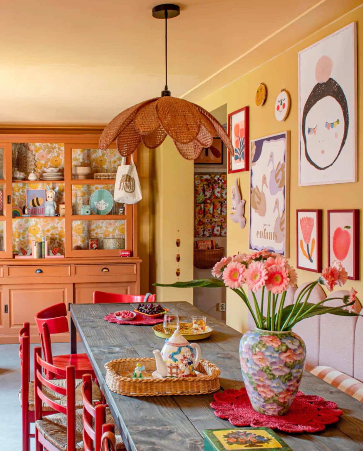 Muurverf 70 Sunroom van Klint. Vloer egaline, eettafel Stoer Metaal, achterwand met eetbank zelfgemaakt. Stoelen, poef en gele lamp vintage. Rotan lamp Leo and Moon. Buffetkast Het Kabinet, geschilderd, tegen de achterwand behang van Swiet. Gordijnen Svanefors van H&M. Posters Atelier Florentine, Moozle, Wolfnoodle en Pansy. Overig onbekend. vtwonen 01-2024 | styling Linda van der Ham | fotografie Caroline Coehorst